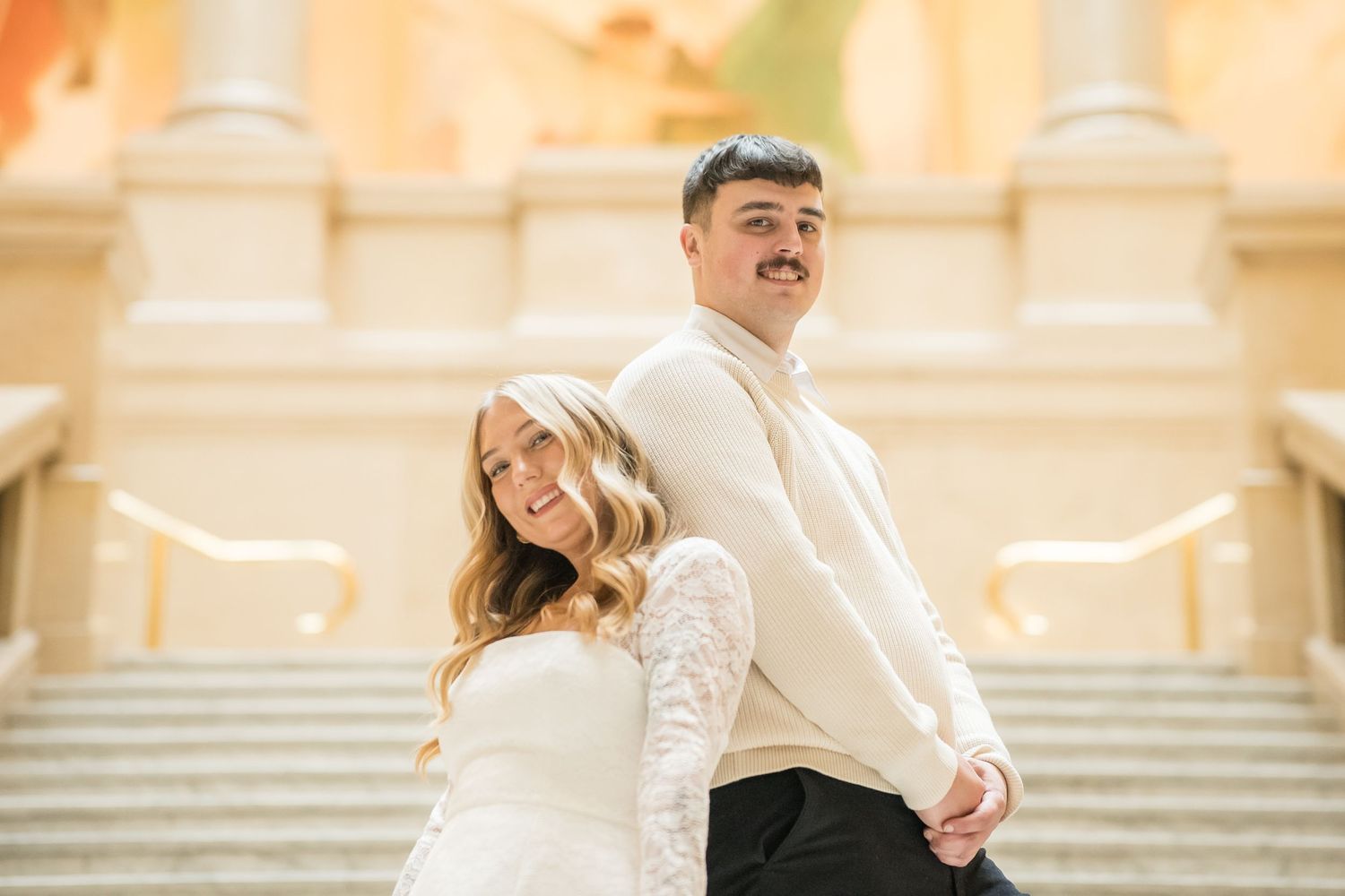 Couple during engagement photography session inside Carnegie Museum of Art, Pittsburgh, PA, marble archways and warm ambient lighting.
