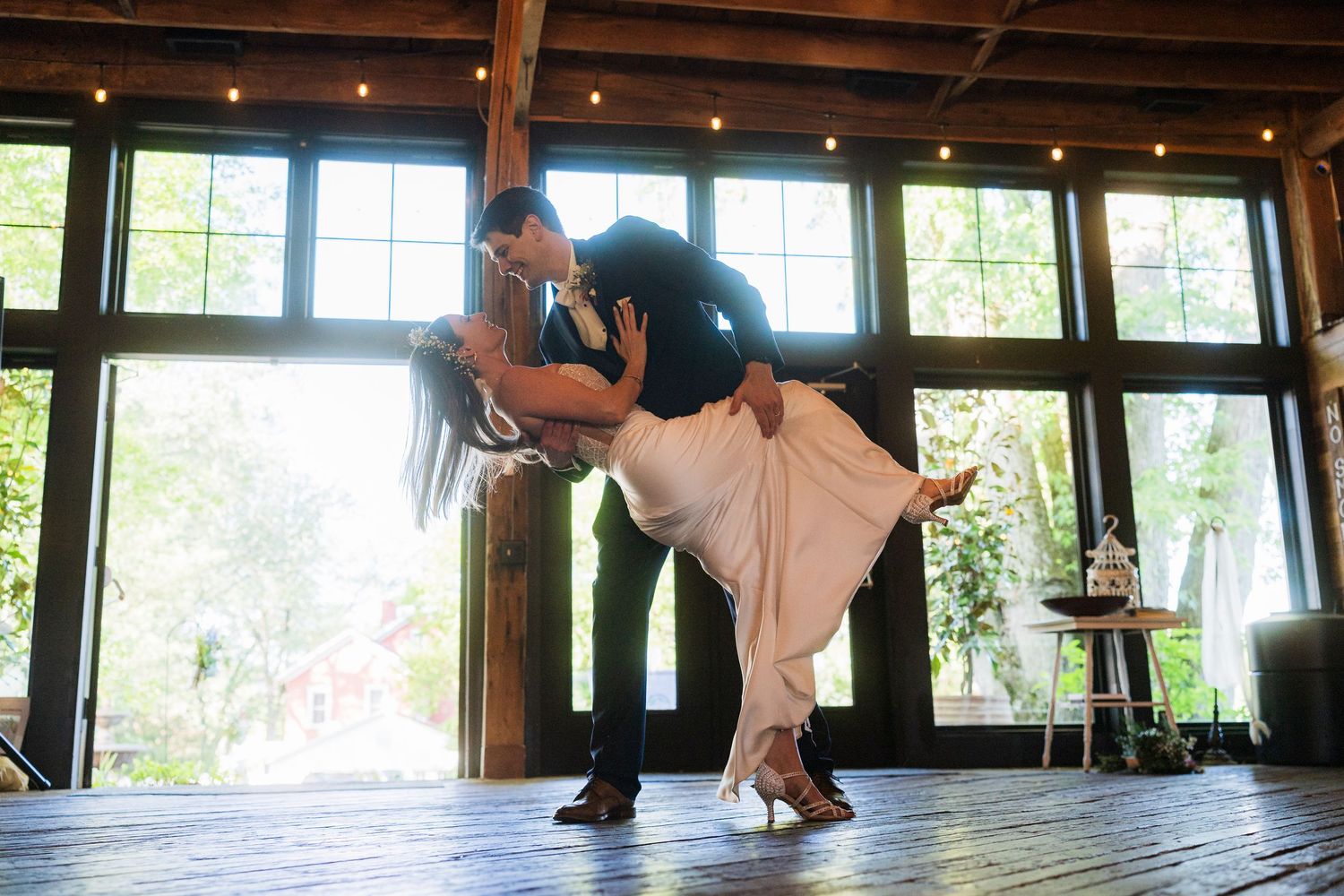 Two dancers performing a romantic dip on a rustic wooden dance floor with large windows.  at shady elms farm pittsburgh pa photography and