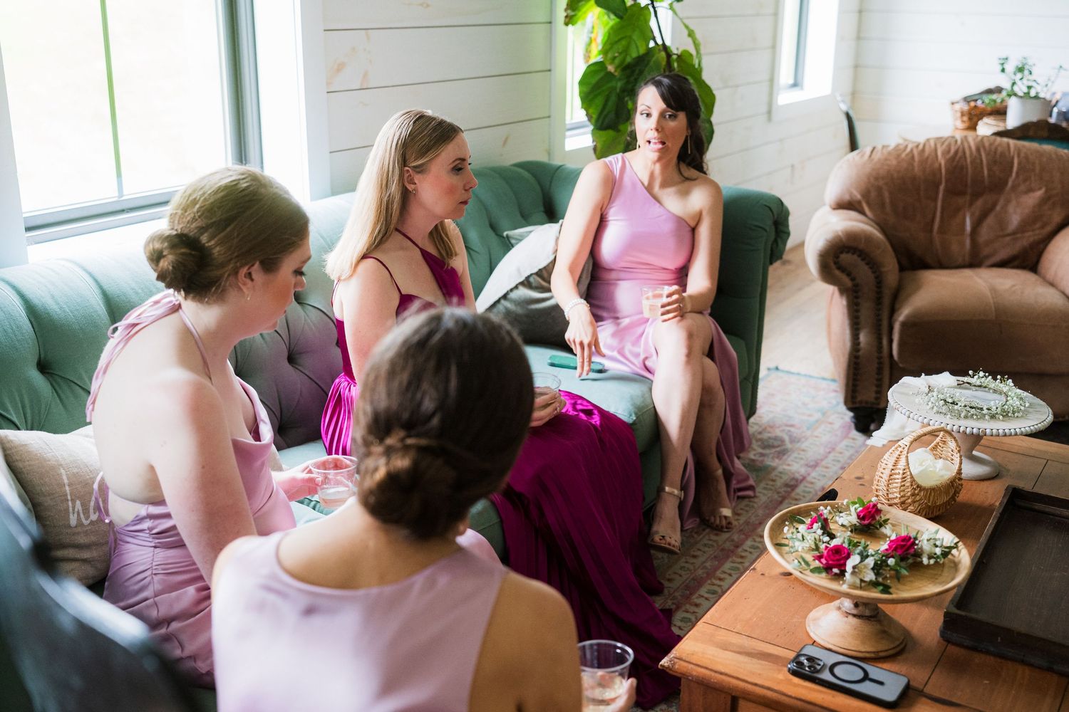 A group in pink outfits gathers in a cozy living room setting with snacks and drinks on a coffee table.  at shady elms farm pittsburgh pa p