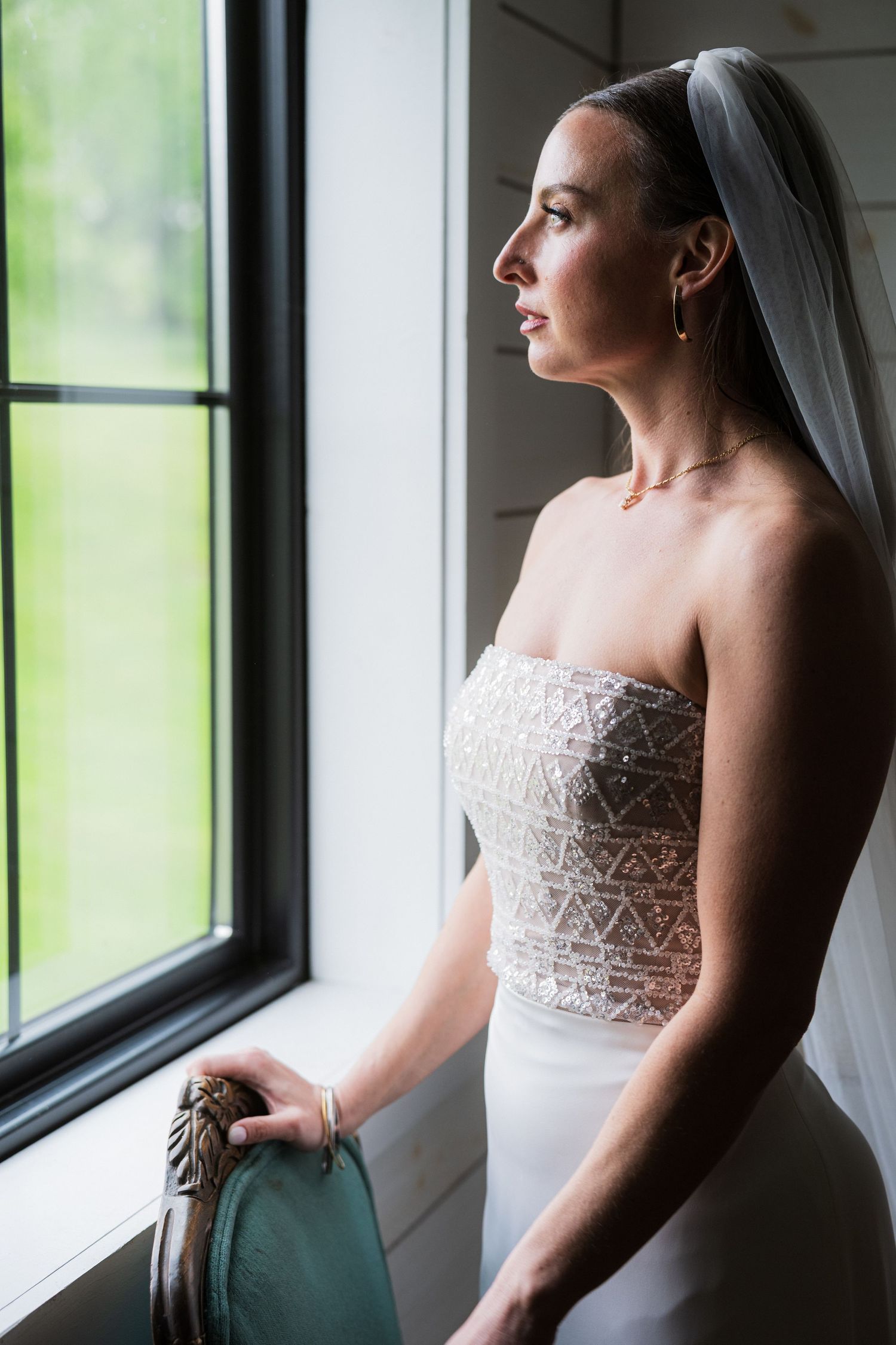 Elegant bridal portraits by a window showing a strapless lace wedding dress in dramatic natural lighting.  at shady elms farm pittsburgh pa