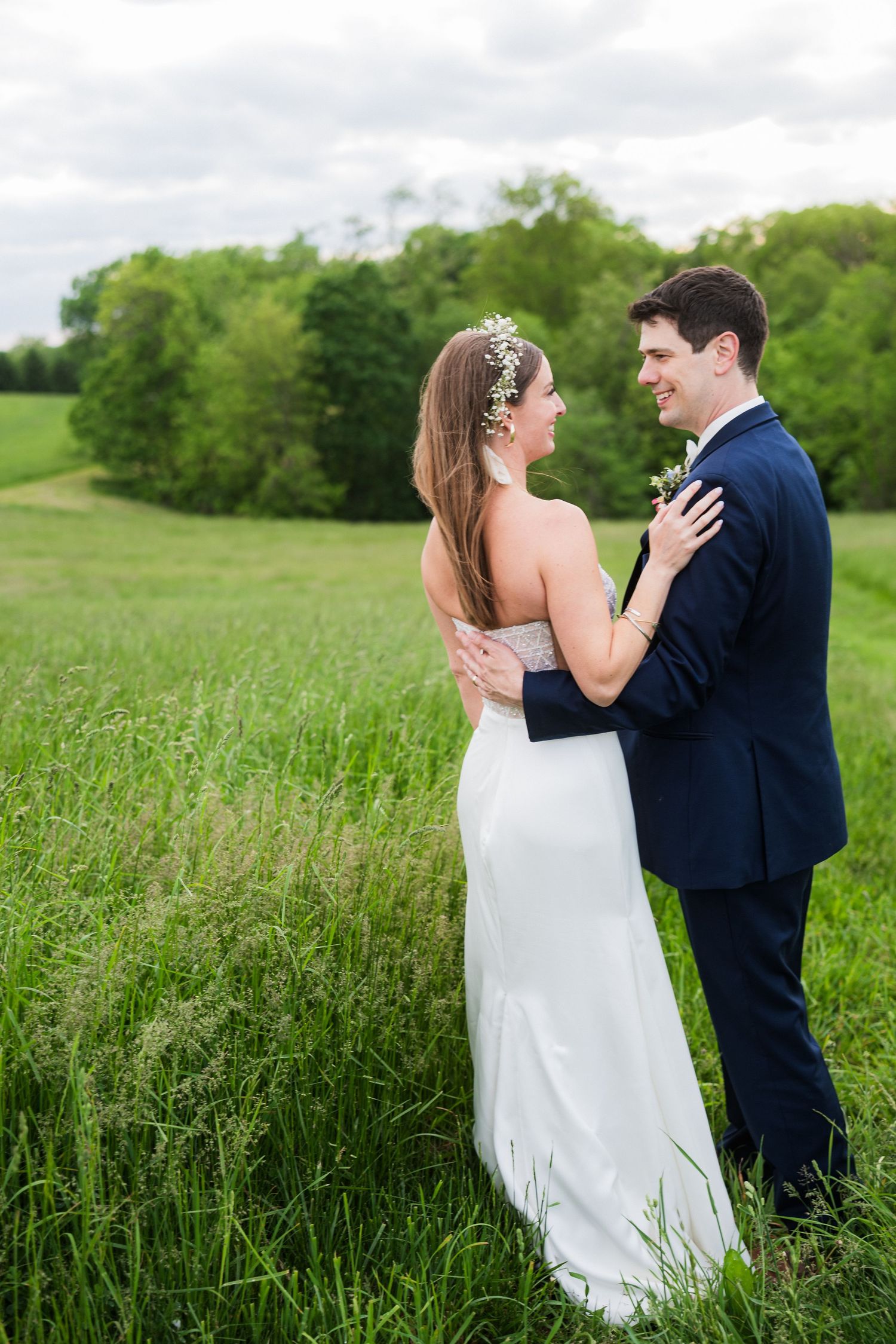 Couple shares tender embrace in field during wedding photoshoot.