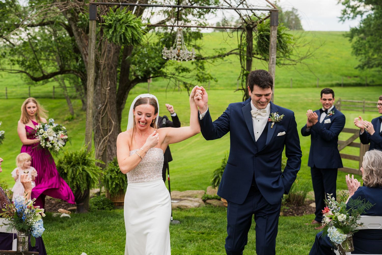 Wedding ceremony taking place on a lush green lawn with trees in the background.