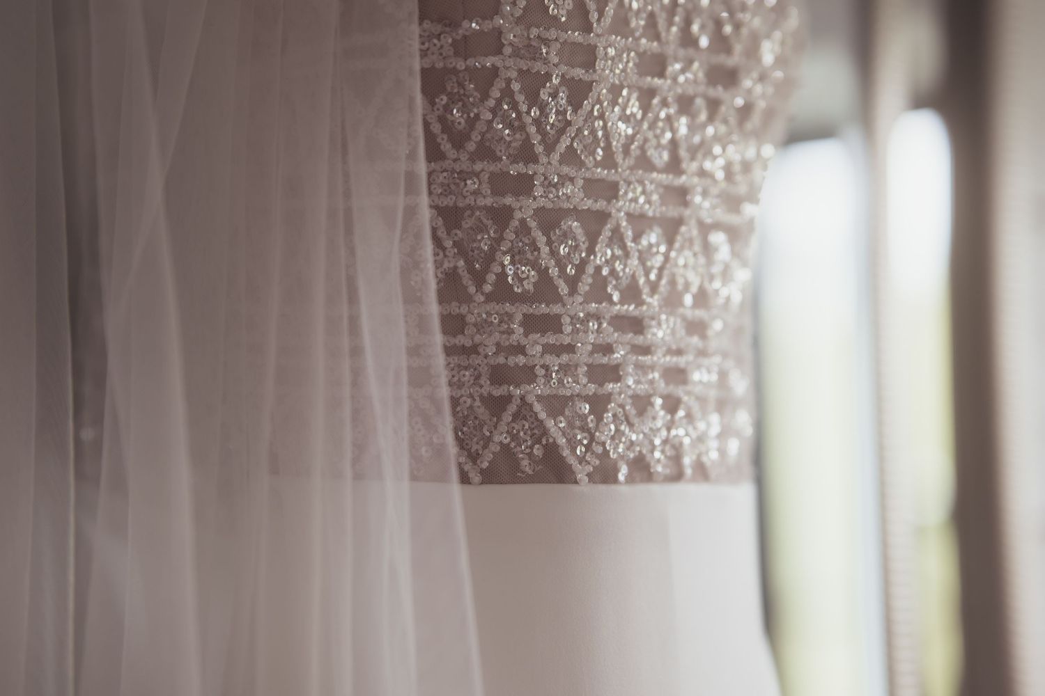 Close-up detail of intricate lace pattern on white wedding dress fabric.