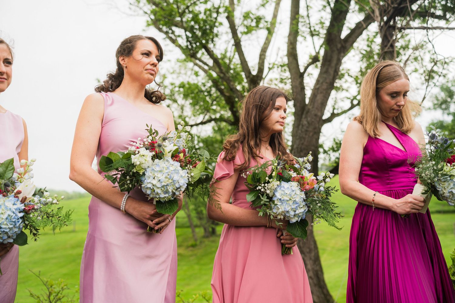 Bridesmaids in various shades of pink and magenta dresses holding pastel bouquets outdoors.  at shady elms farm pittsburgh pa photography a