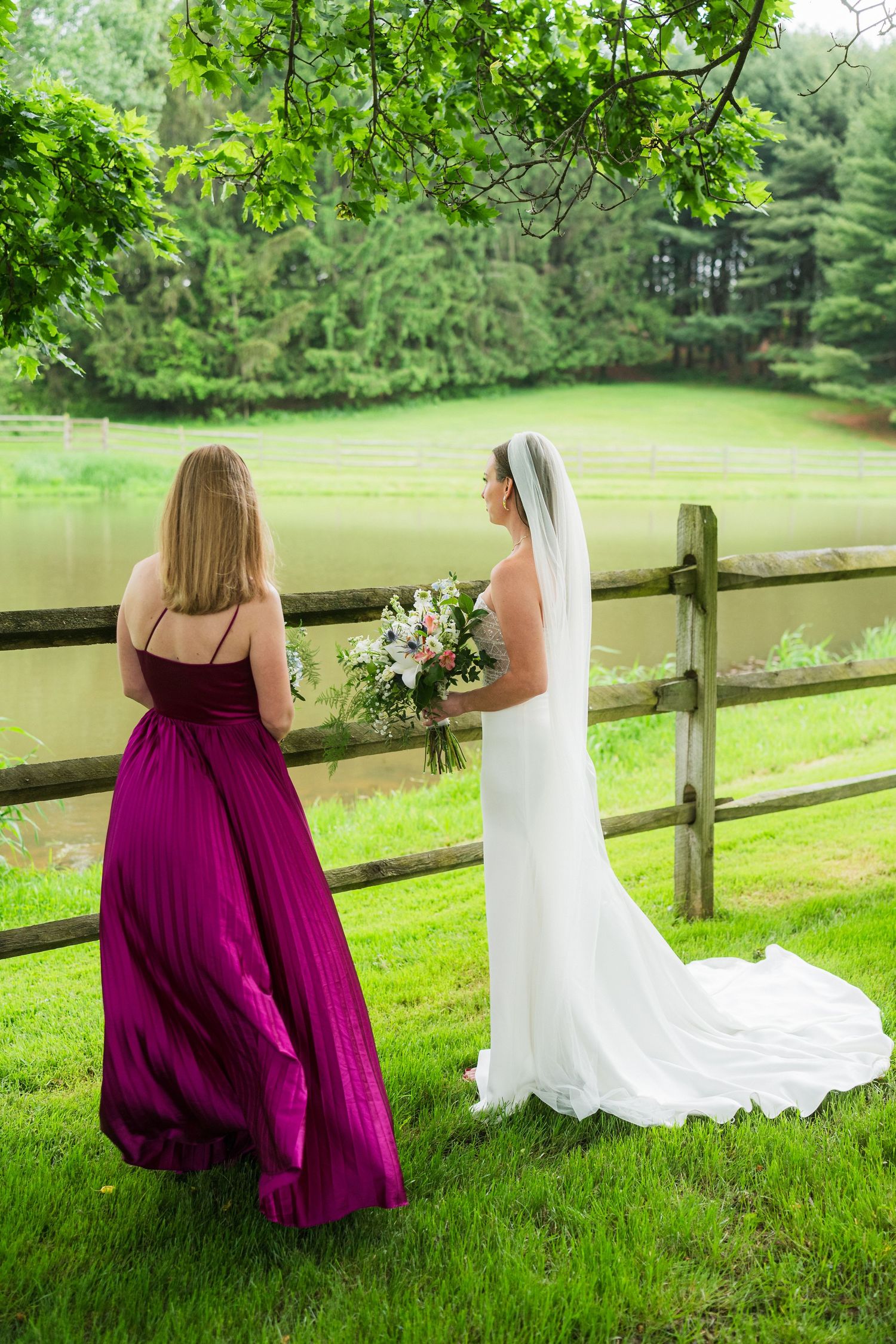 A scenic wedding photo by a pond with green trees and wooden fence.  at shady elms farm pittsburgh pa photography and video