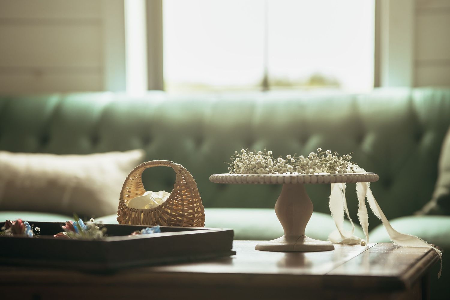 Wedding accessories and decor arranged on a mint green tufted couch in soft natural lighting.