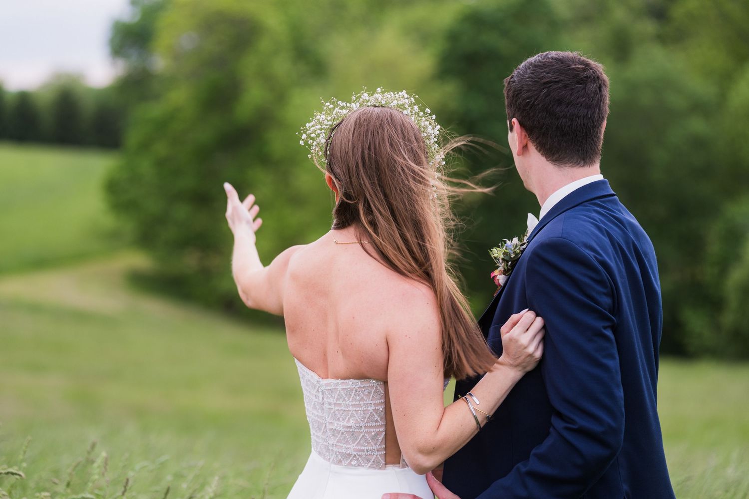 Newlyweds share a private moment on a grassy hillside.