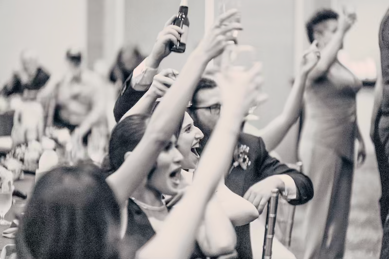 Black and white crowd photo showing raised hands and arms during a celebratory moment at a pittsburgh airport wedding.