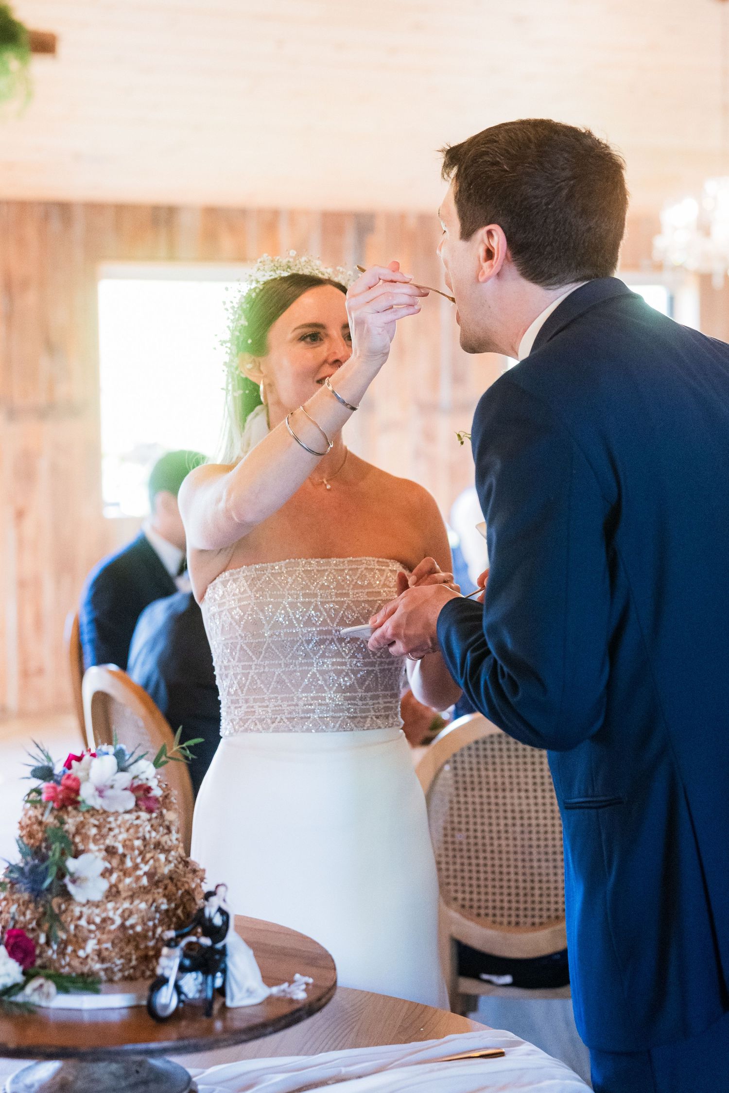 Newlyweds feed each other wedding cake during their reception celebration.