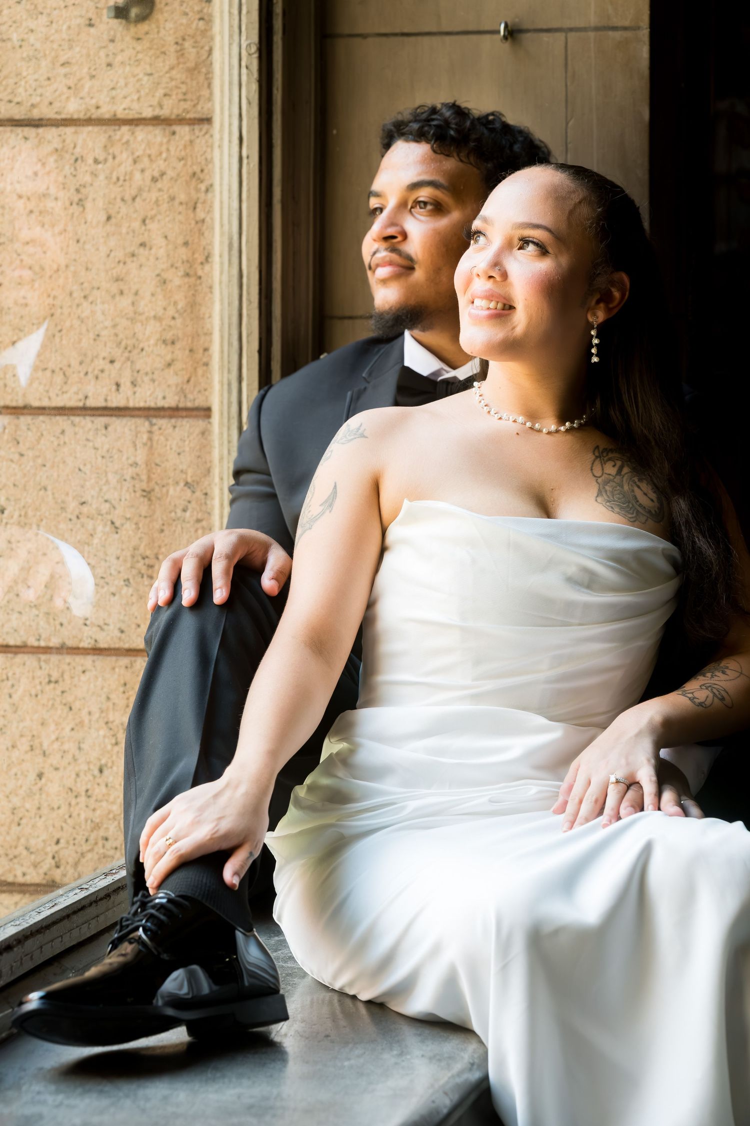 Couple embracing beneath Romanesque stone arches during moody editorial engagement session at Allegheny County Courthouse, Pittsburgh.