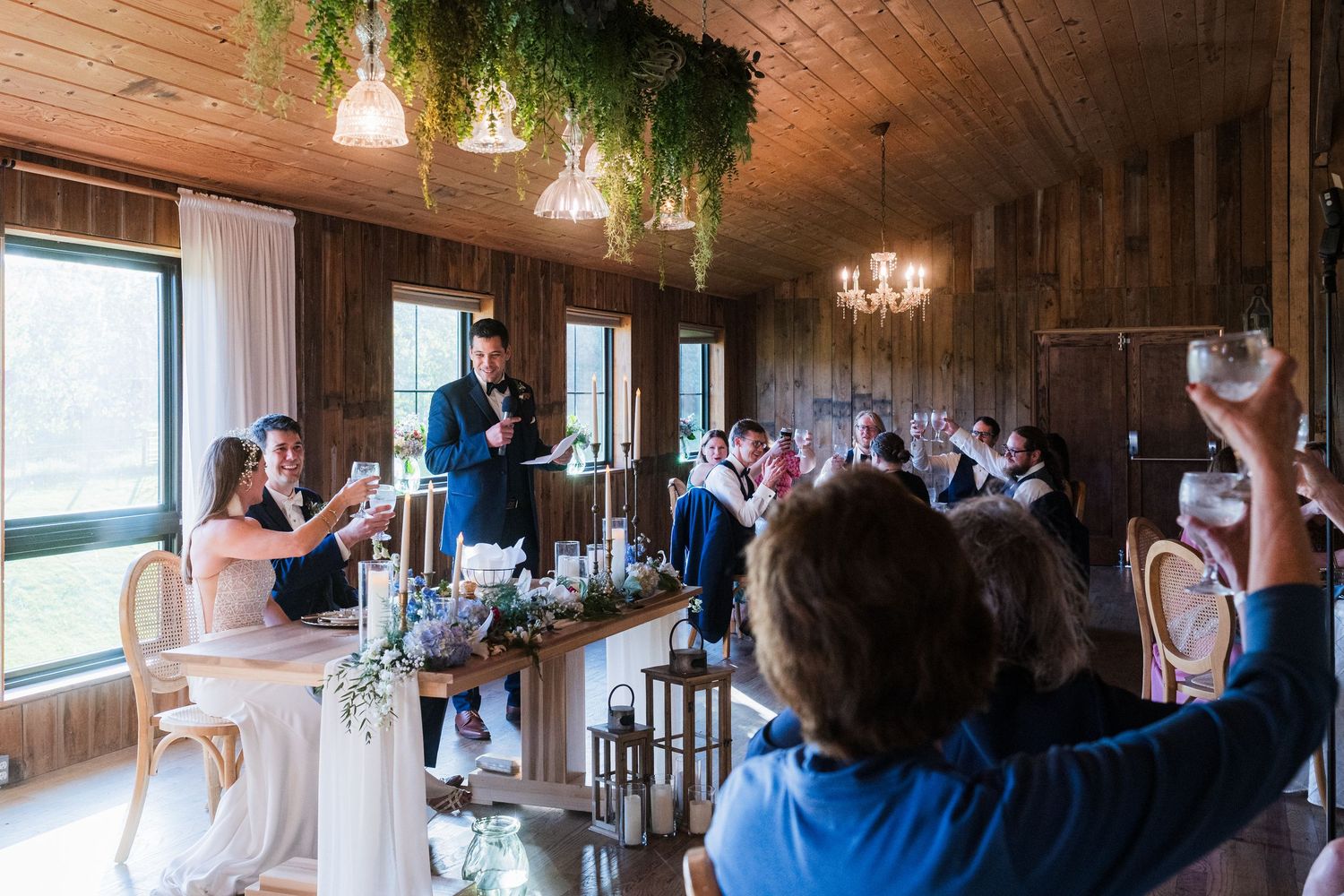 Wide angle view of a rustic wooden reception venue with hanging chandeliers and greenery.  at shady elms farm pittsburgh pa photography and