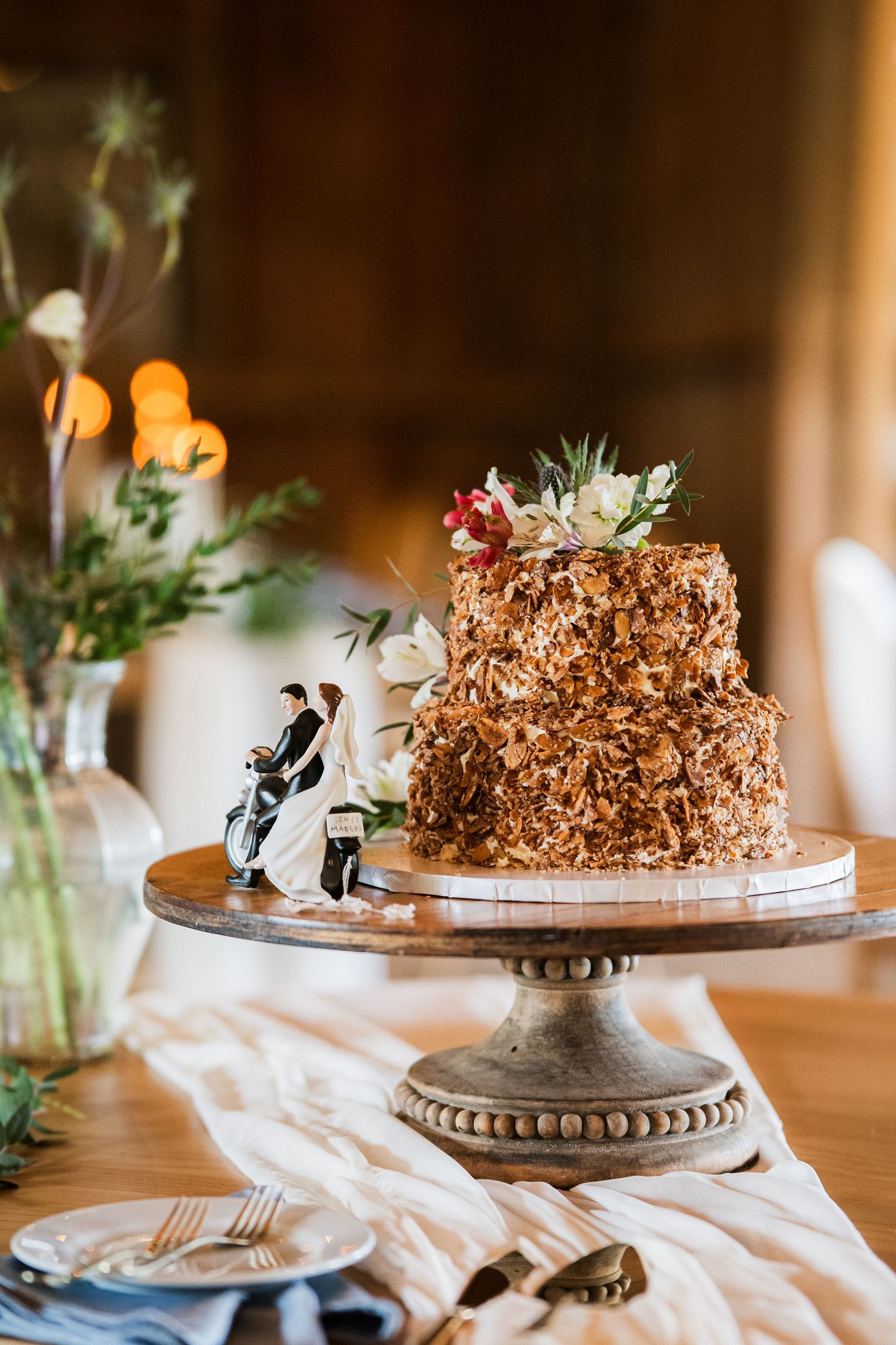 Two-tiered wedding chocolate wedding cake with succulent topper displayed on an ornate silver cake stand.