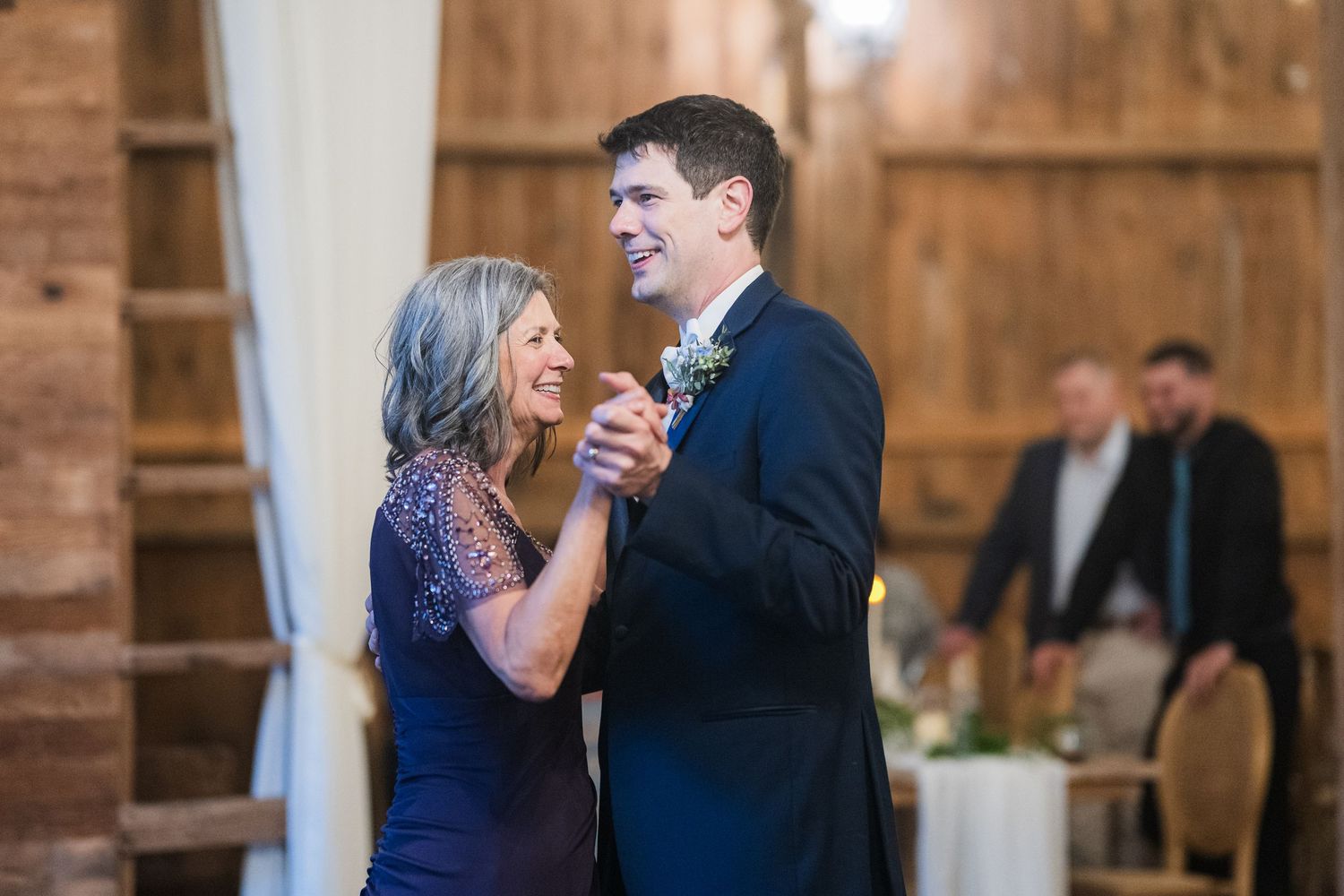 Joyful dancing couple sharing a tender moment on their wedding day in a rustic barn setting.