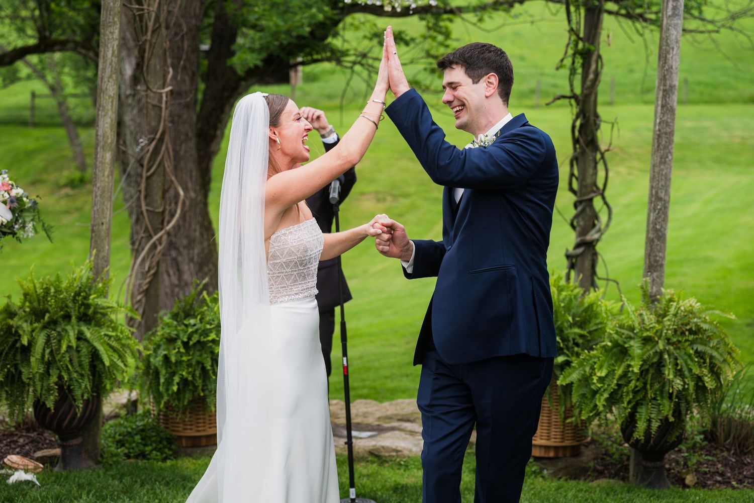 Newlyweds celebrating with arms raised in joy during outdoor garden ceremony.  at shady elms farm pittsburgh pa photography and video