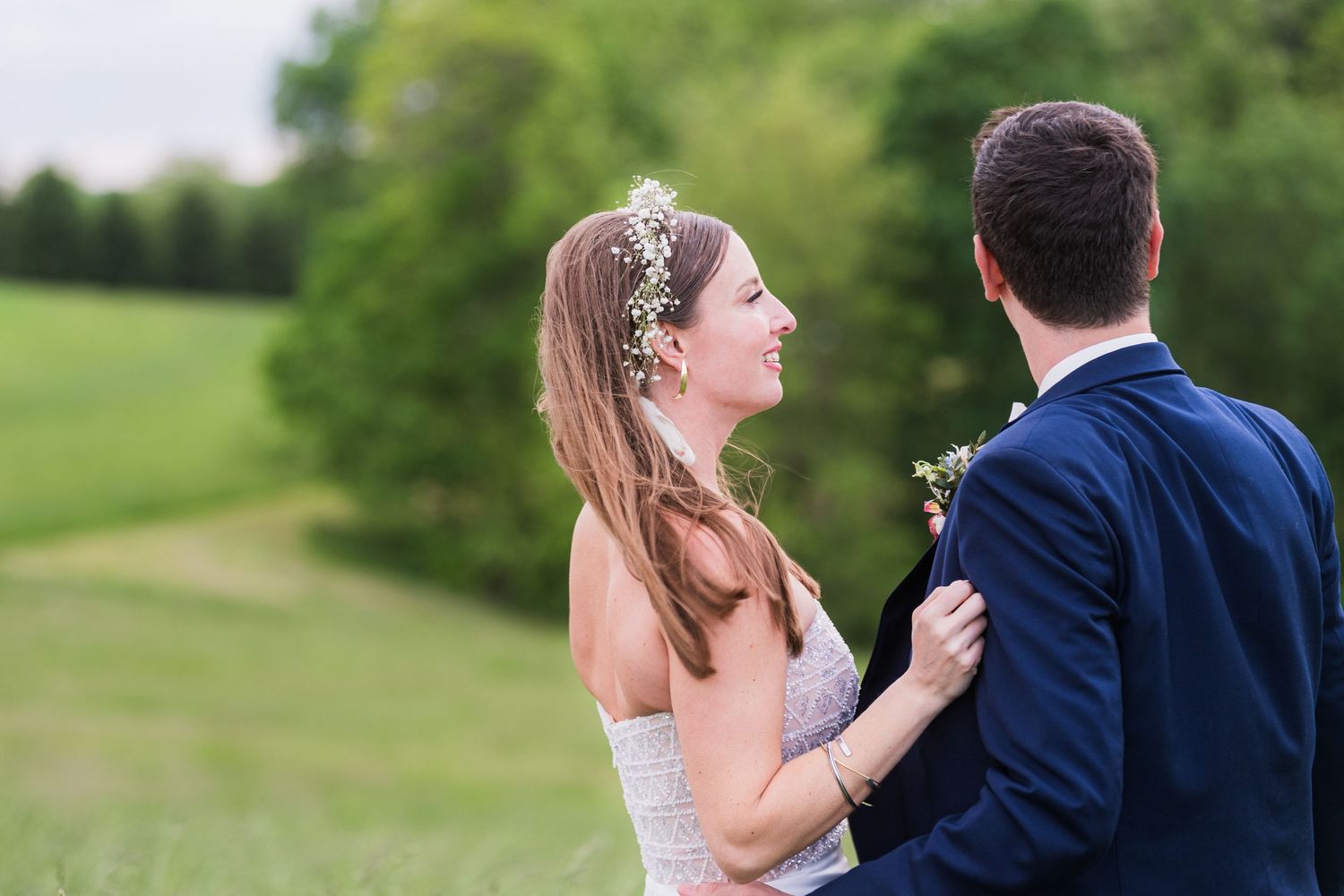 A couple in wedding attire share a joyful moment together on a lush green hillside.  at shady elms farm pittsburgh pa photography and video