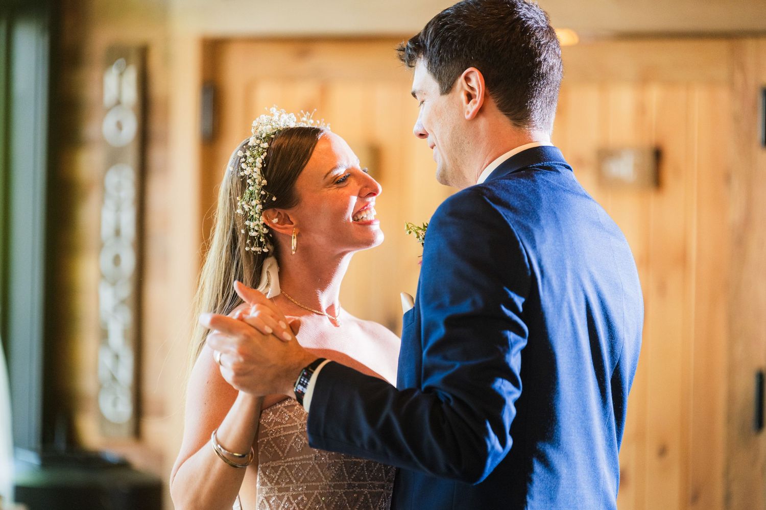A couple shares a joyful moment during their first dance at a rustic wedding venue.