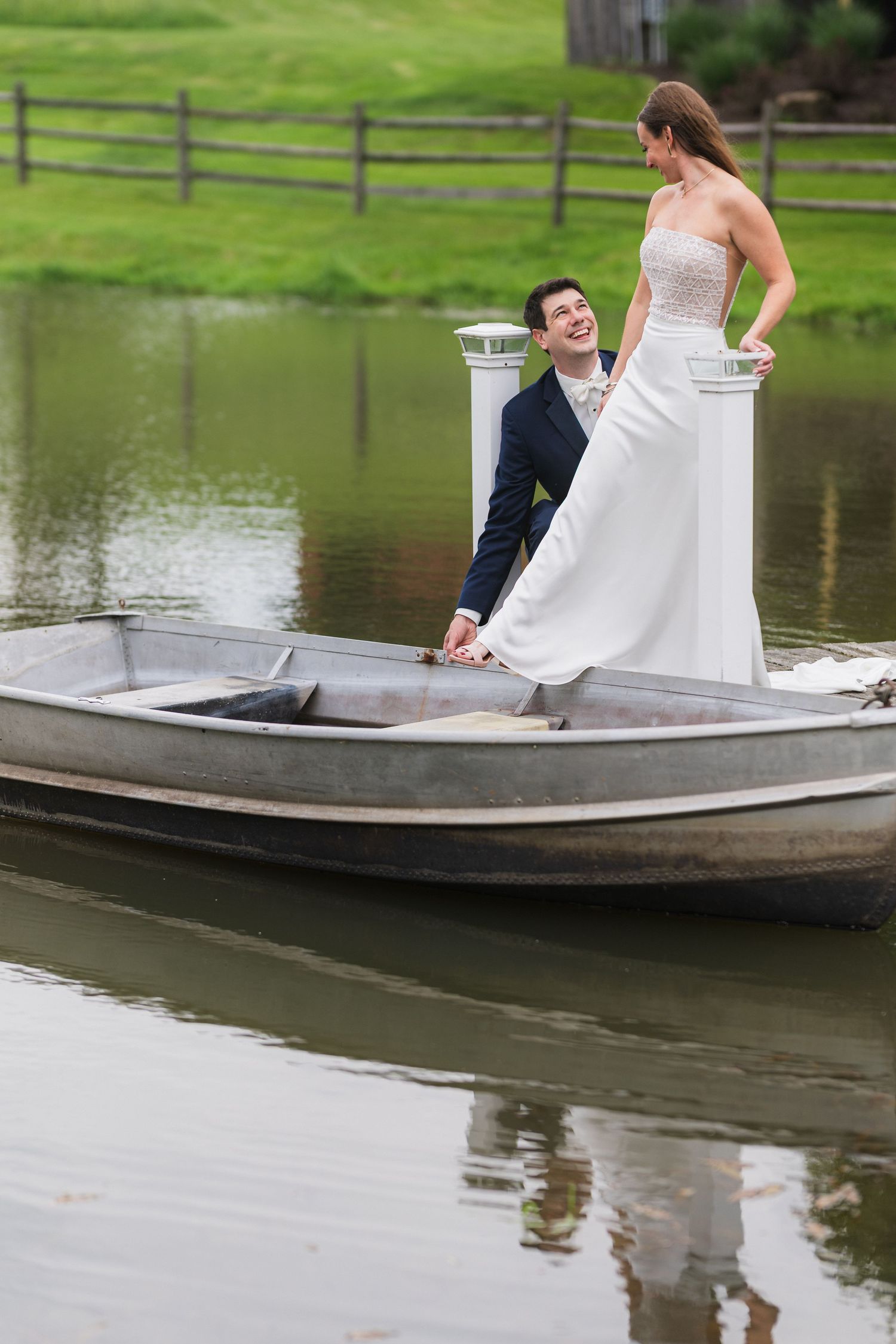 A couple shares a playful moment while standing on a small boat in a pond.  at shady elms farm pittsburgh pa photography and video