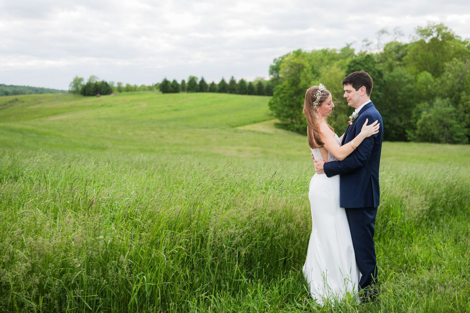 Wedding couple embracing in a scenic meadow with rolling hills in the background.  at shady elms farm pittsburgh pa photography and video