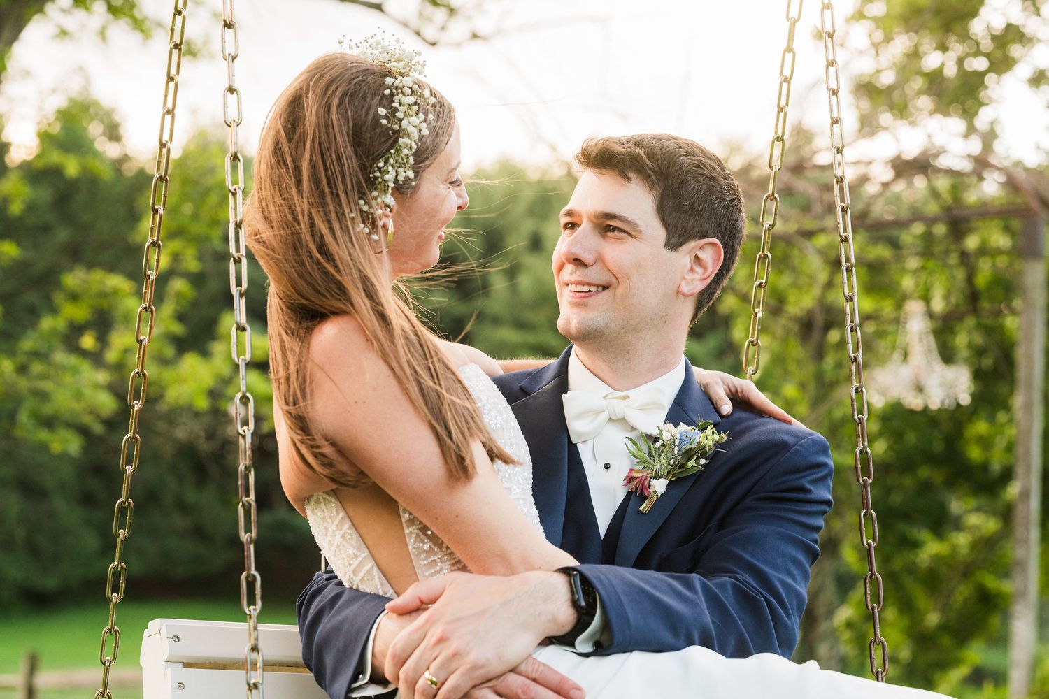 A romantic wedding couple moment on a garden swing surrounded by greenery.