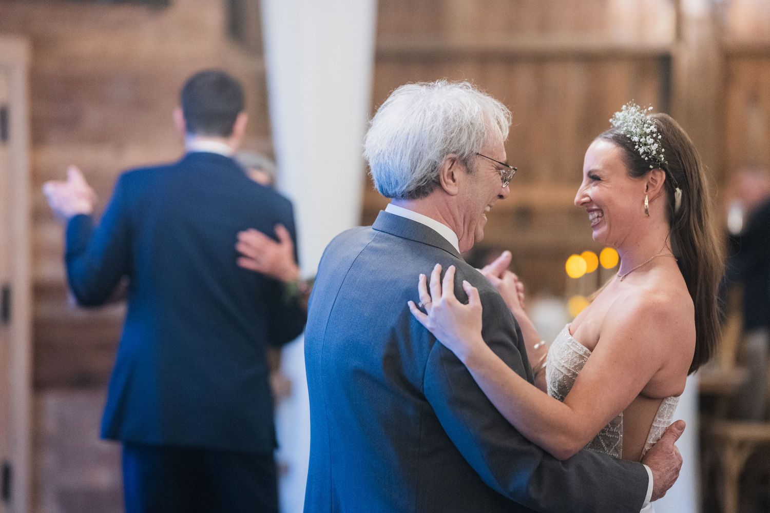 Wedding reception guests dancing together in a rustic barn venue with wooden walls and warm lighting.