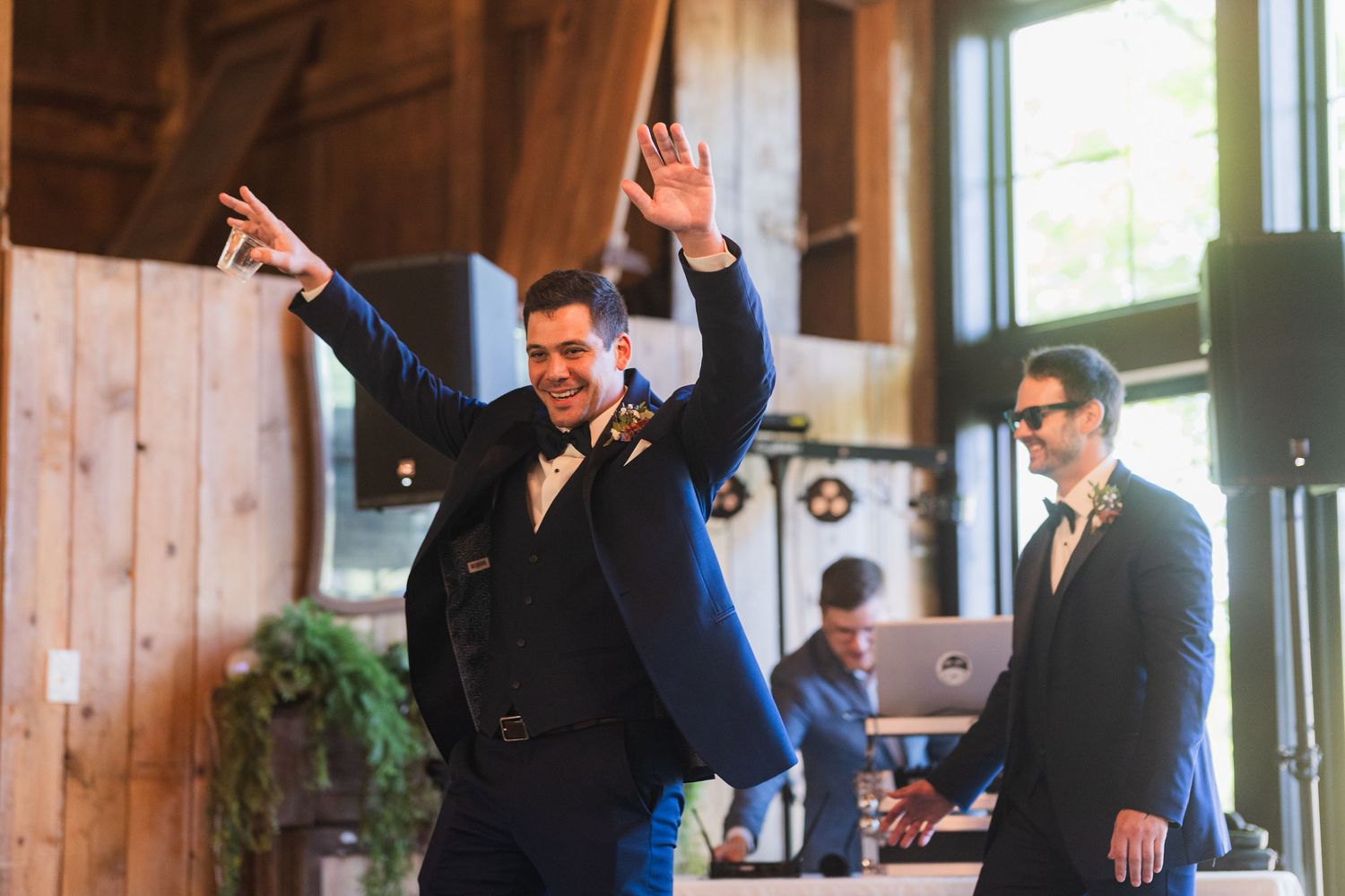 Celebration in a rustic wooden barn venue with raised arms and festive energy.