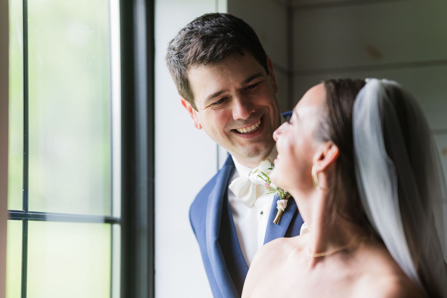 Joyful couple sharing a candid moment by a window during their wedding celebration.  at shady elms farm pittsburgh pa photography and video