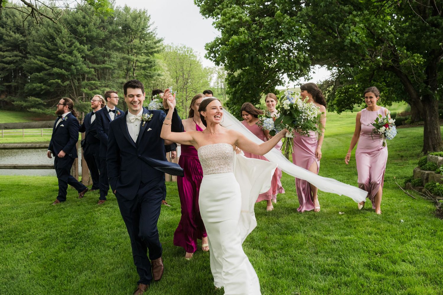 Wedding party celebrates on a green lawn with joyful jumping poses.  at shady elms farm pittsburgh pa photography and video