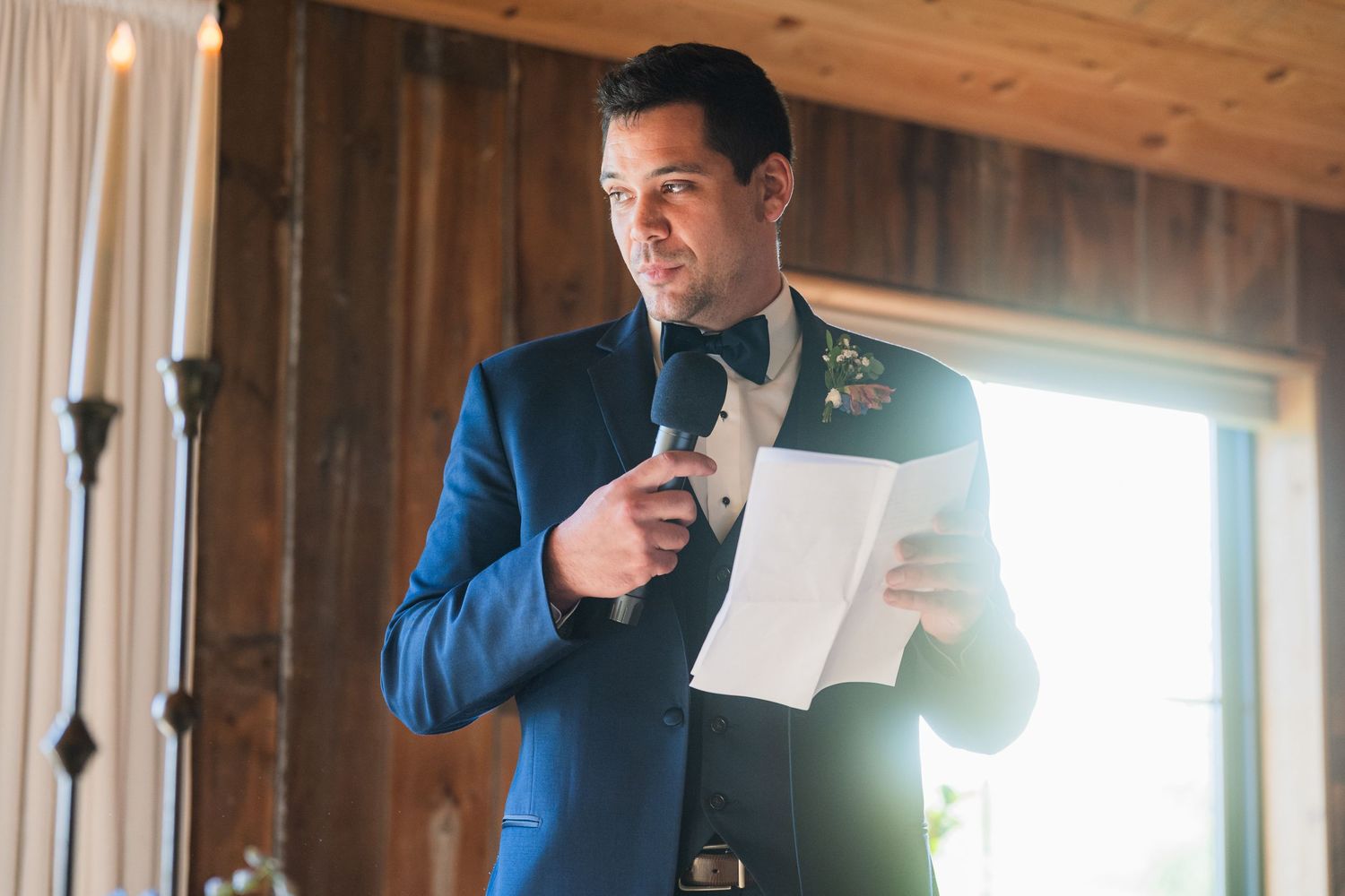 A formal speech being delivered in a rustic wooden venue with natural lighting.