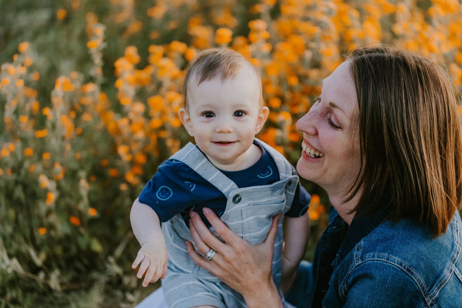 A tender moment shared between parent and child amidst vibrant orange wildflowers on a sunny day.