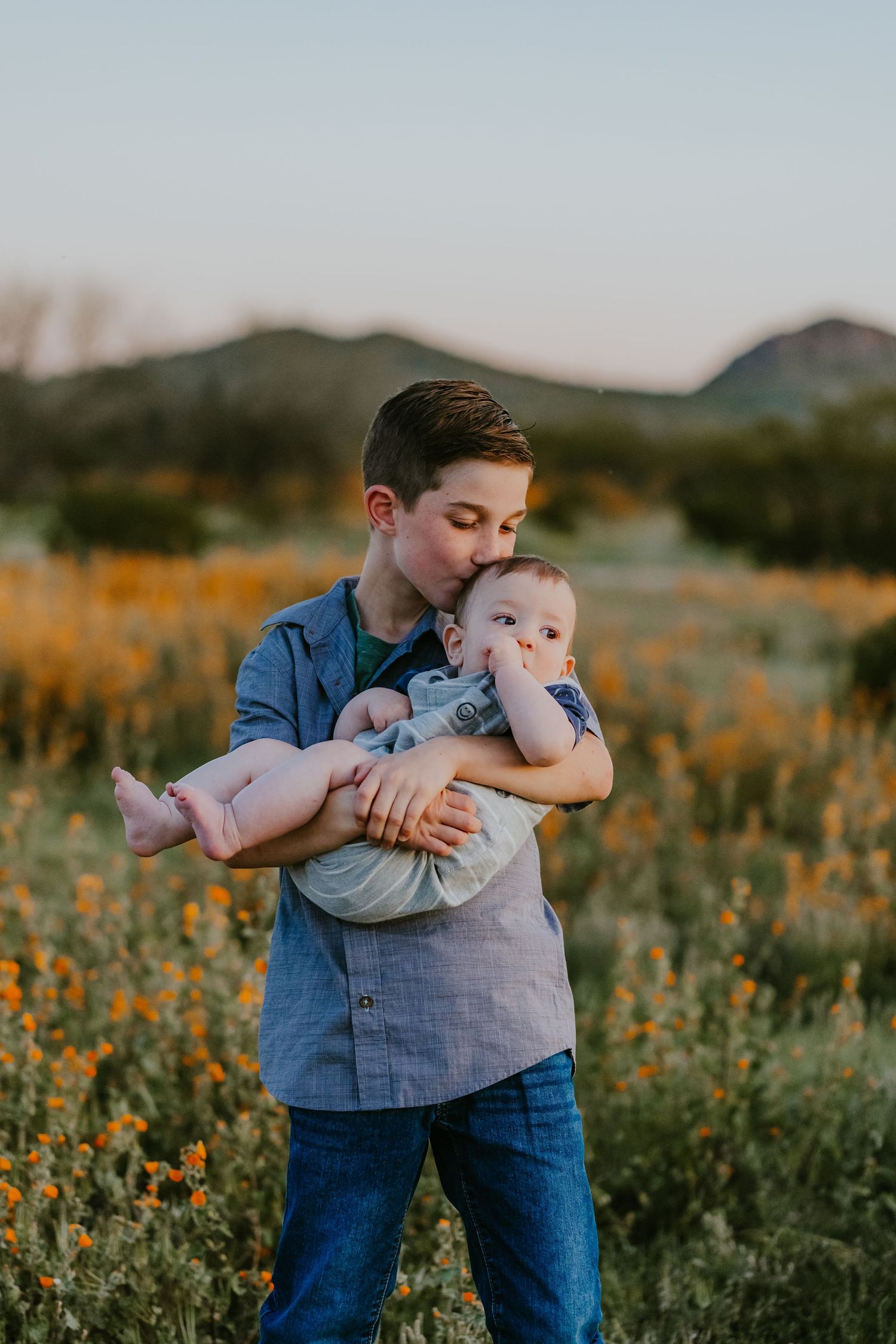 A parent and child share tender moments while playing in a wildflower meadow at sunset.