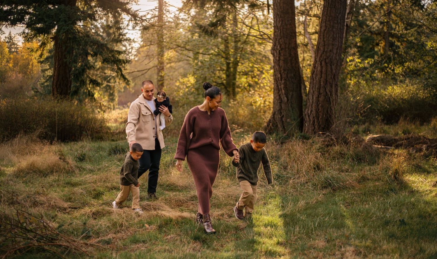 Family walking together through a lush forest park on a sunny autumn day, enjoying nature outdoors.