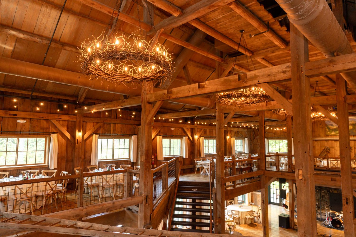 The Barn on the Pemi wedding indoor reception space area upstairs view with stairs chandeliers dancefloor and tables Plymouth NH