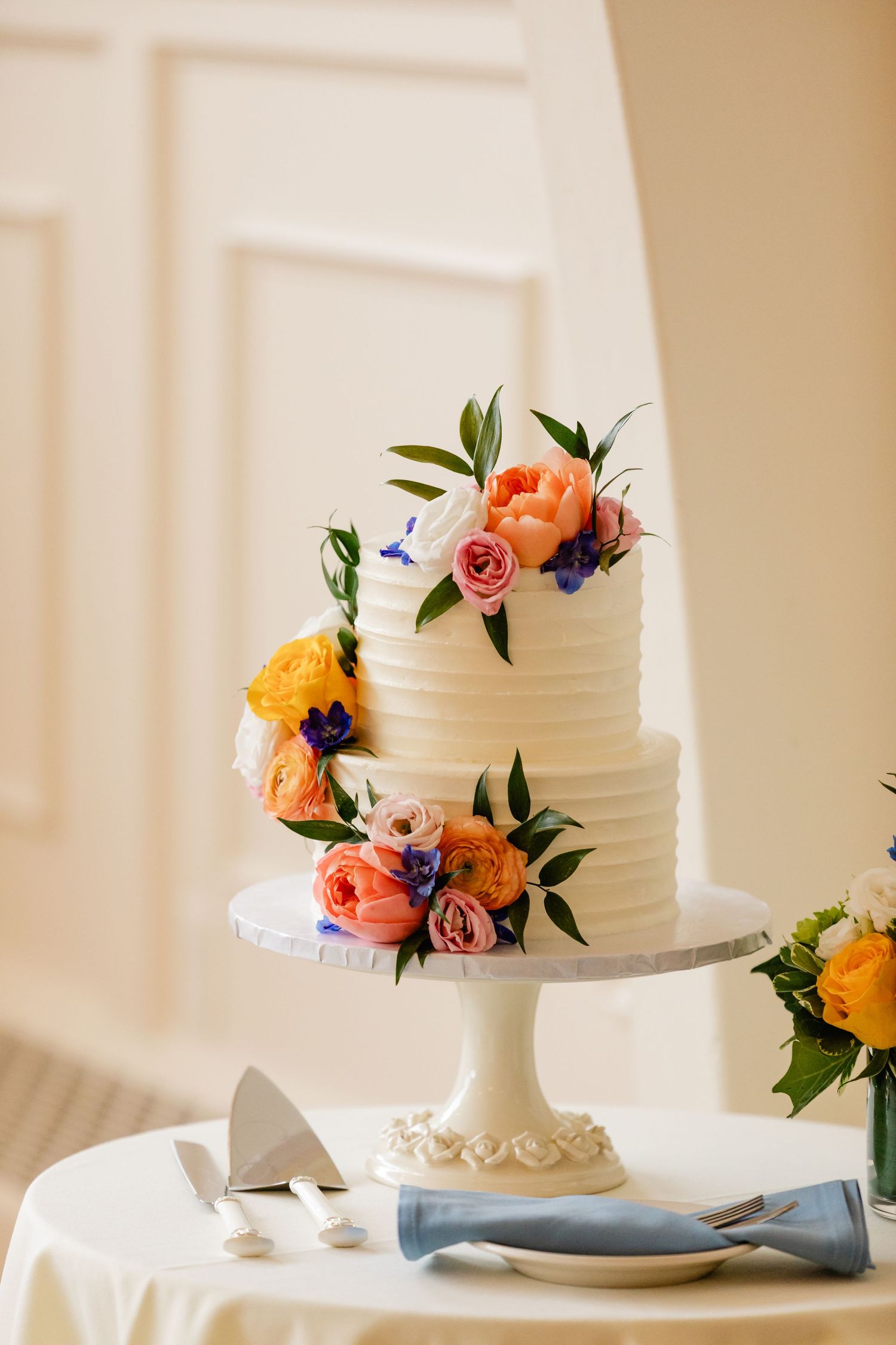 2 tier white wedding cake with colorful fresh floral accents in light and bright room at Northampton Country Club in Northampton, MA
