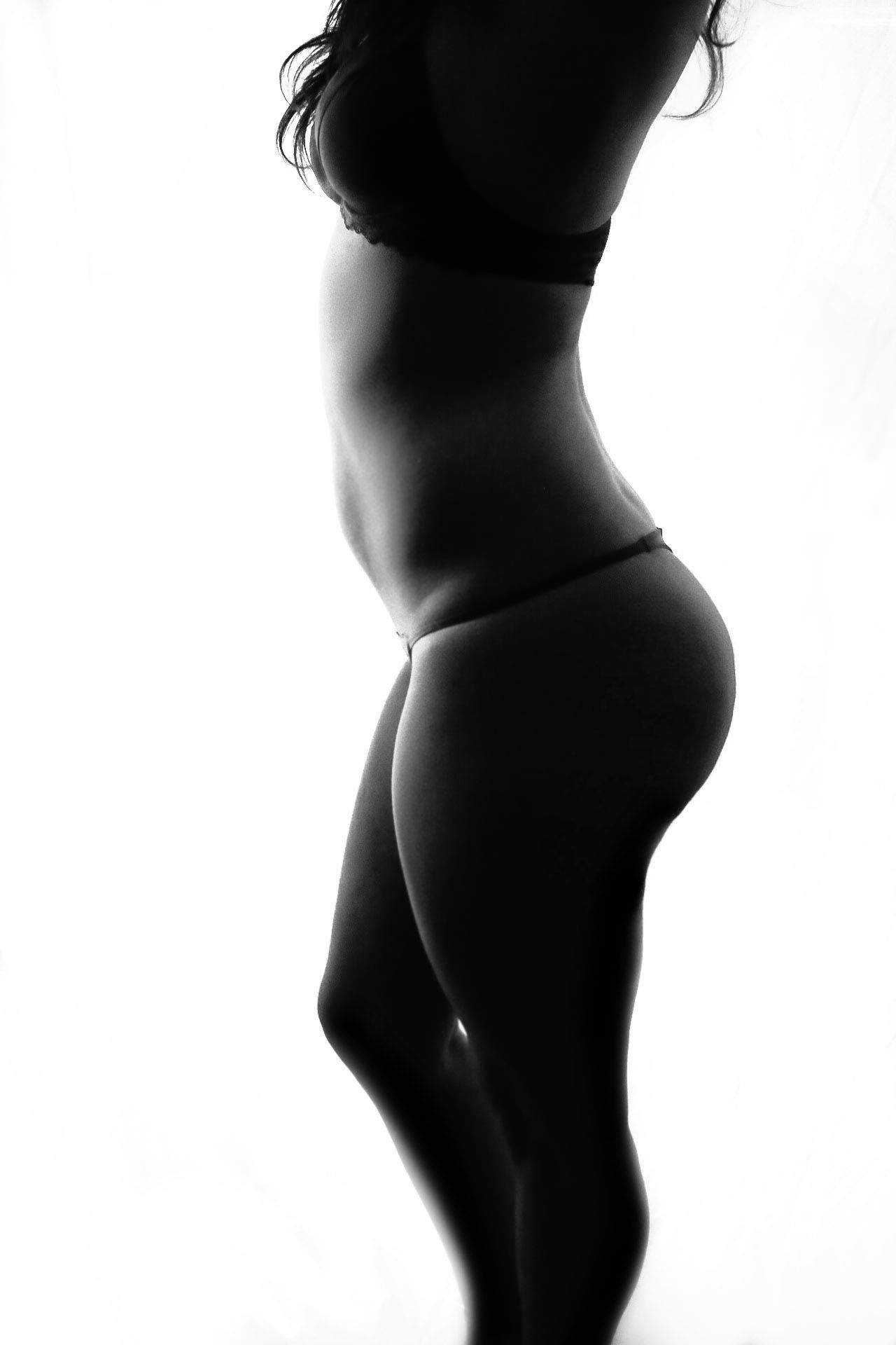 Black and white silhouette of a woman in lingerie posed against a white background.