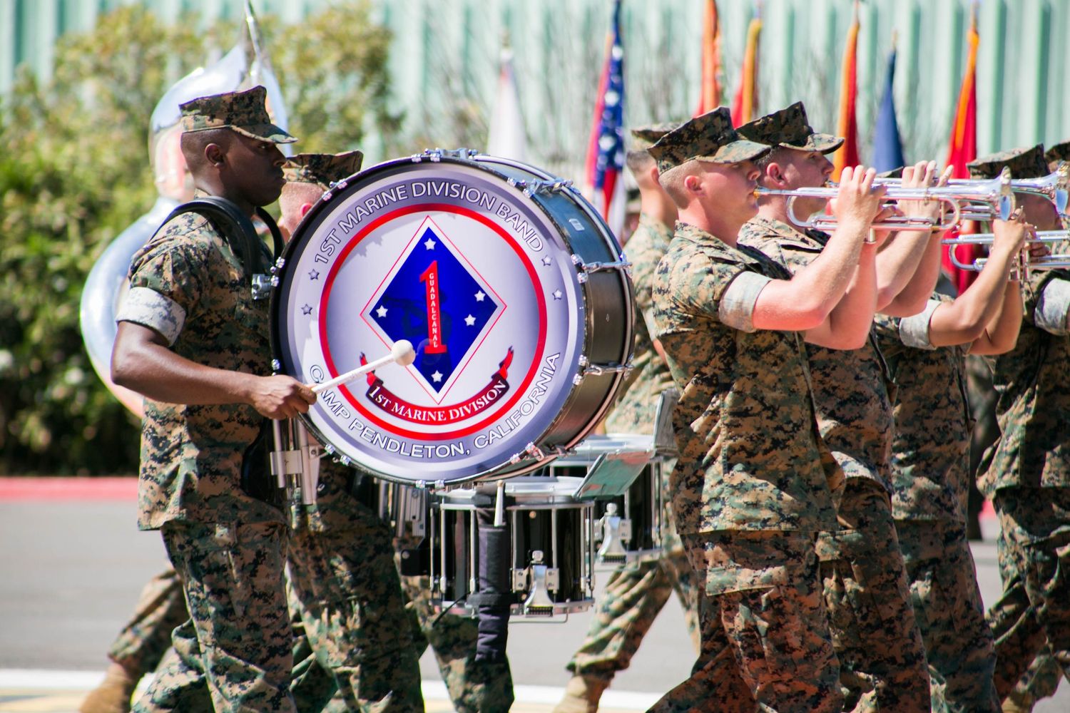 US Marine Corps band members march in uniform during an official military parade ceremony outdoors.