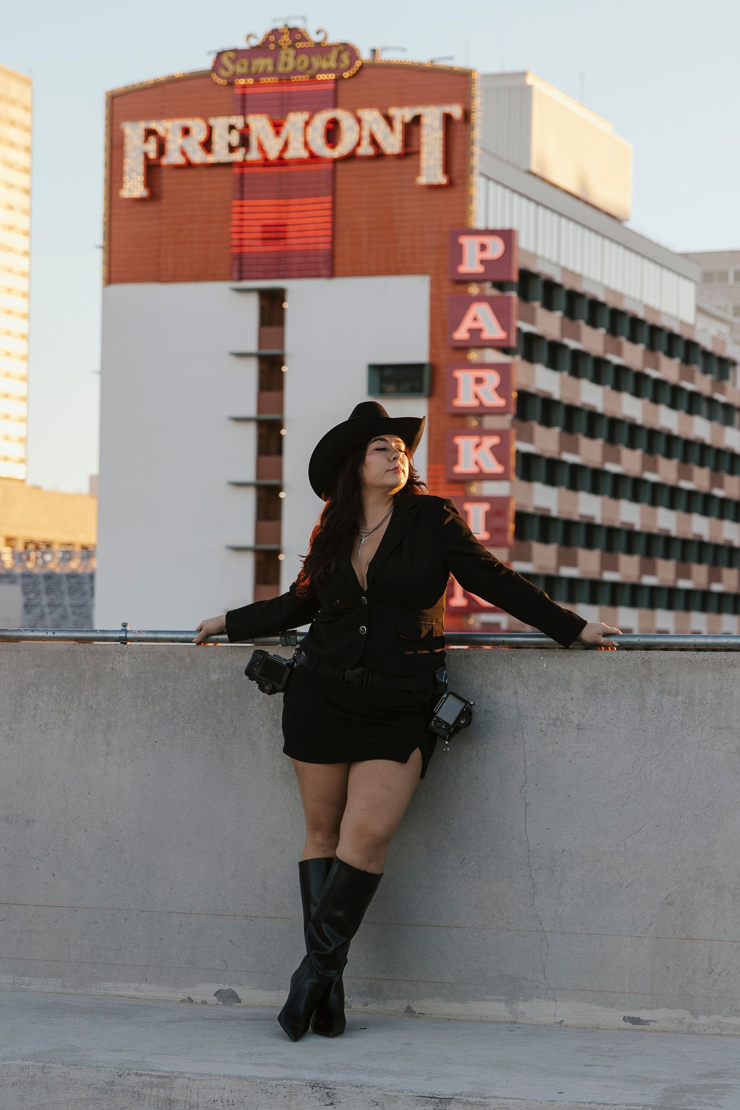 Stylish woman in black outfit and cowboy hat posing on rooftop near Fremont Street Las Vegas.