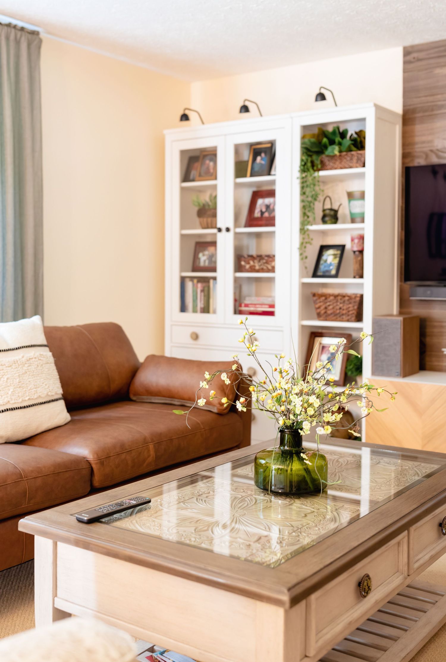 Living room with brown leather couch, built-in shelving, and marble coffee table.