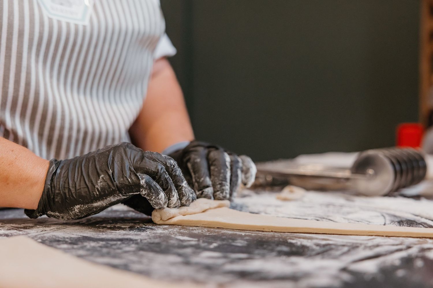 Hands kneading dough on a flour-dusted surface in a kitchen setting.