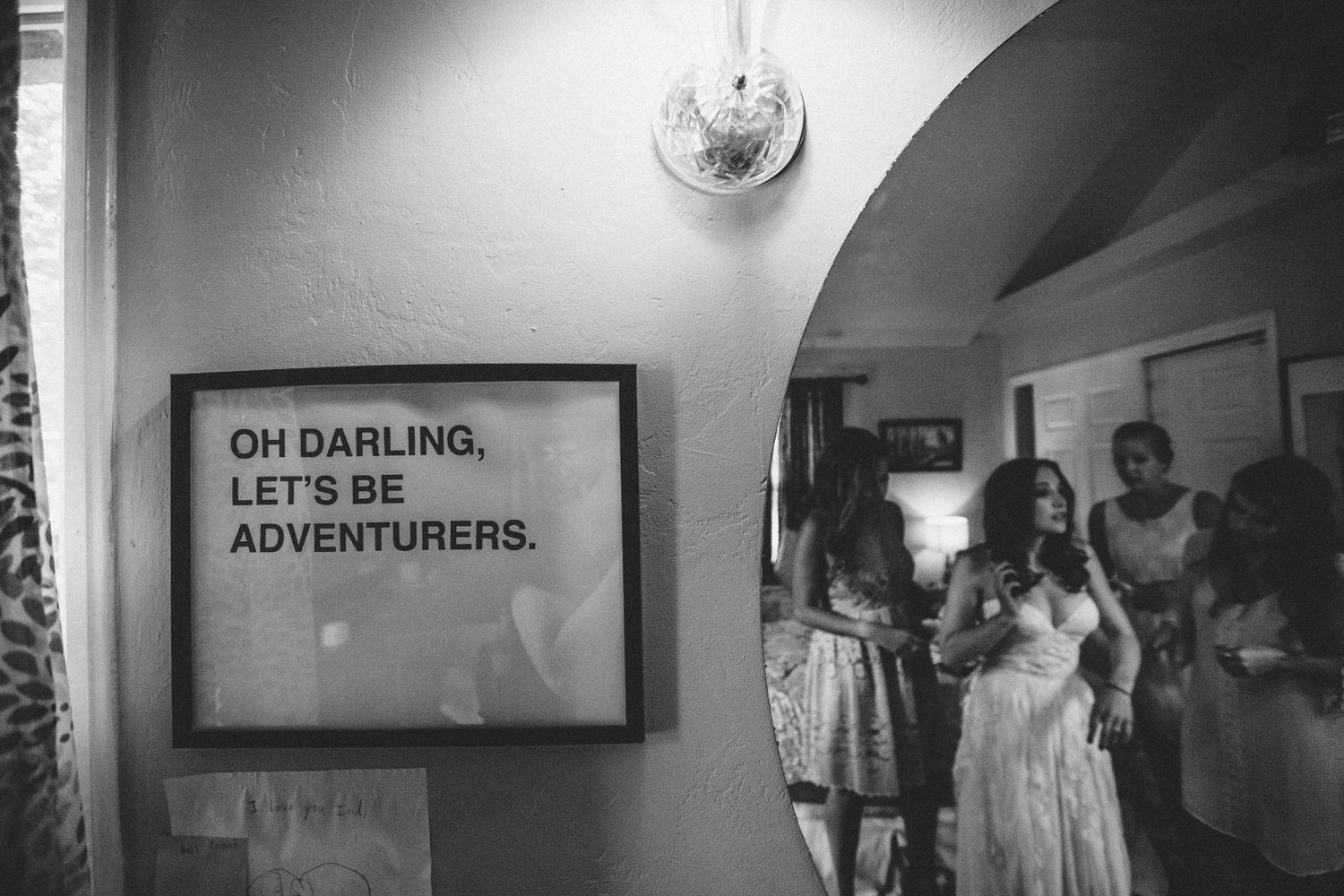 Bride  getting ready with bridesmaids under  “Oh Darling, Let’s Be Adventurers” sign, setting the tone for a fun-filled celebration.