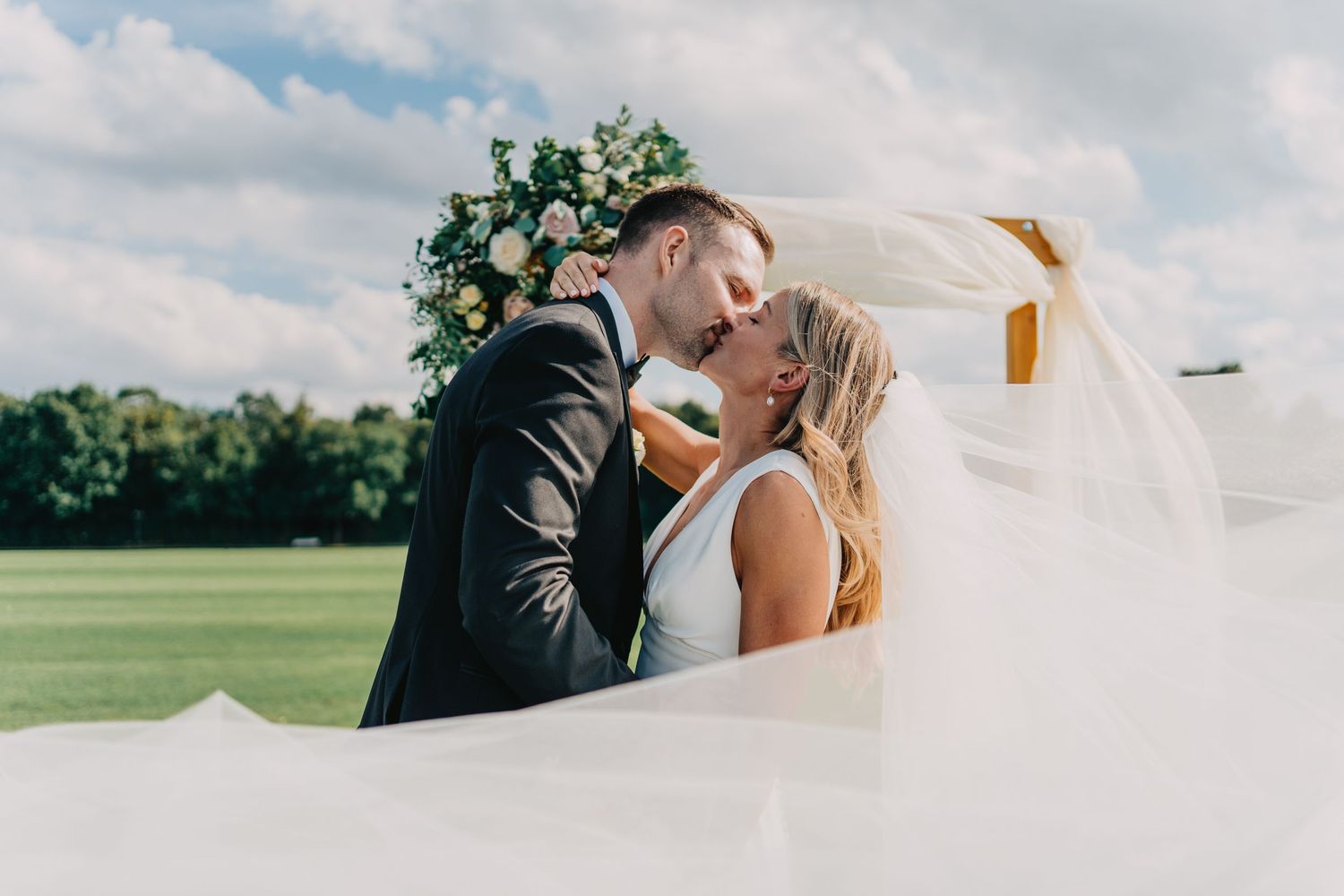 Romantic wedding portrait in a green field with flowing white veil.