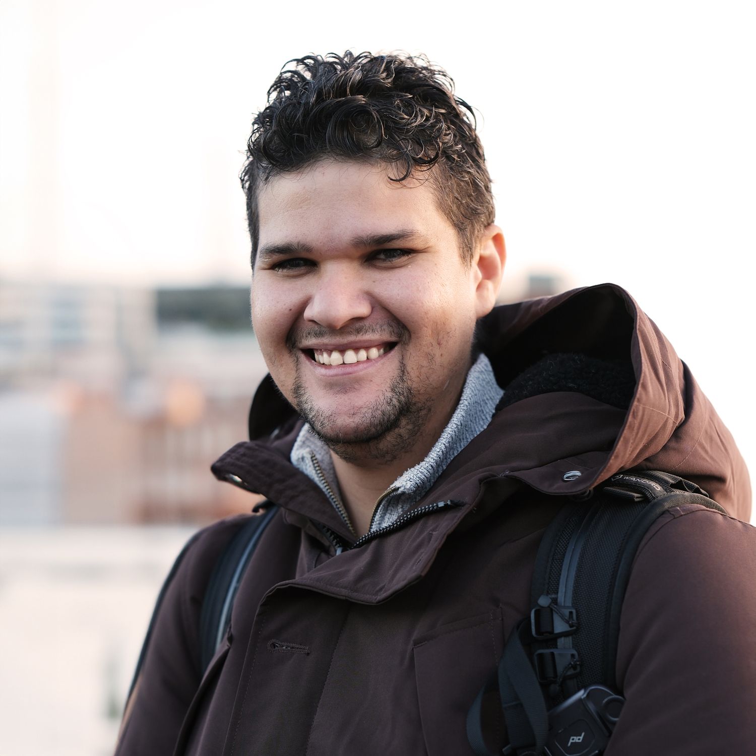 A portrait of a person in a winter coat smiling warmly at the camera.