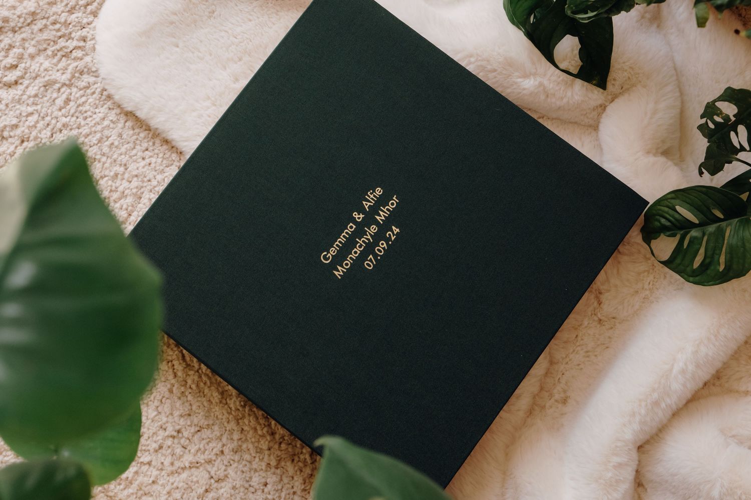 Dark green linen wedding album with gold foil names embossed on the front cover
