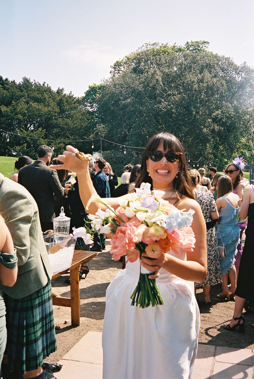 Effortlessly chic glasgow bride toasting the photographer with an oyster at her relaxed wedding party at Dunglass Estate, East Lothian
