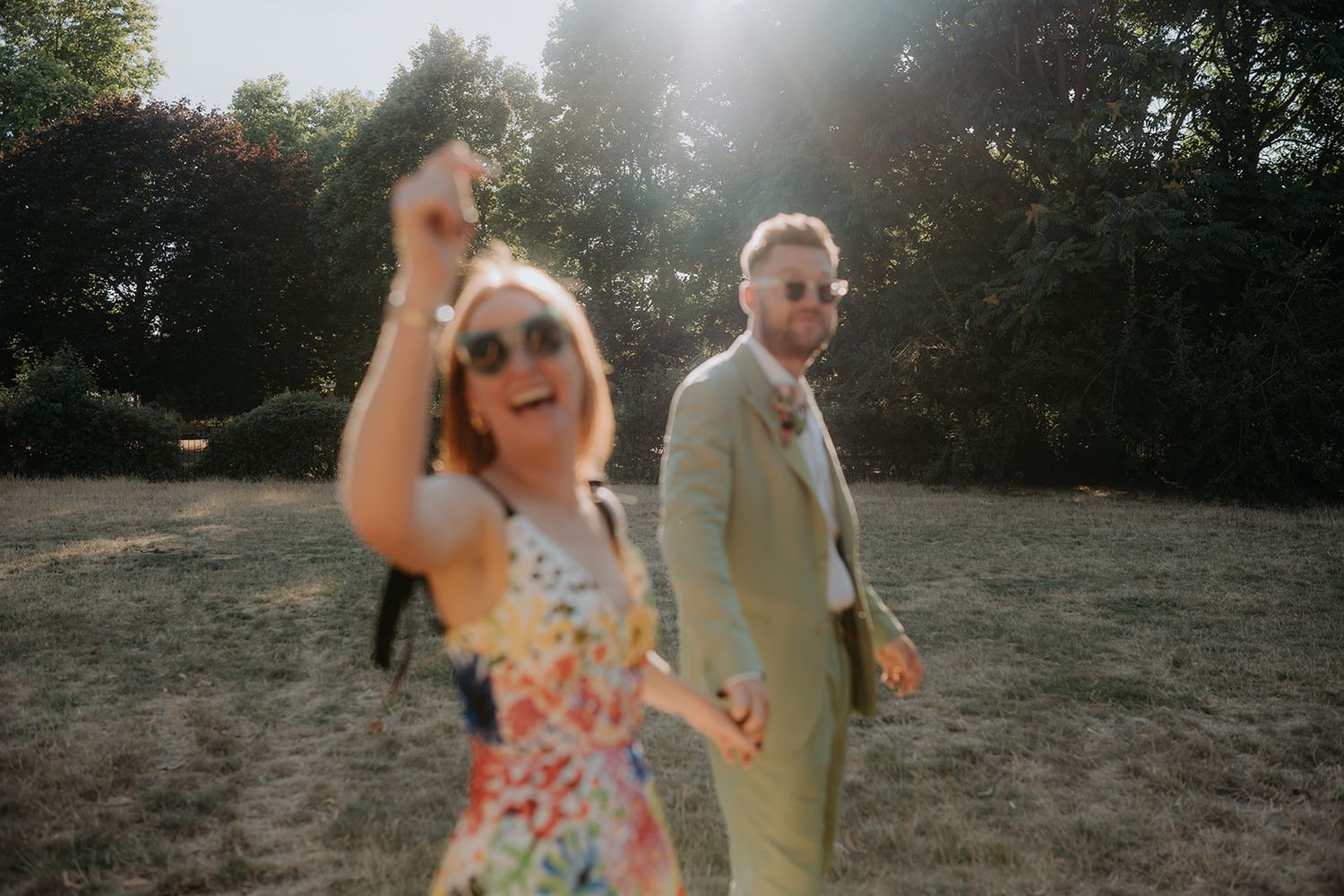 Creative London couple laughing in golden sunlight in a London Park after their casual and colourful Southwark registry office wedding.