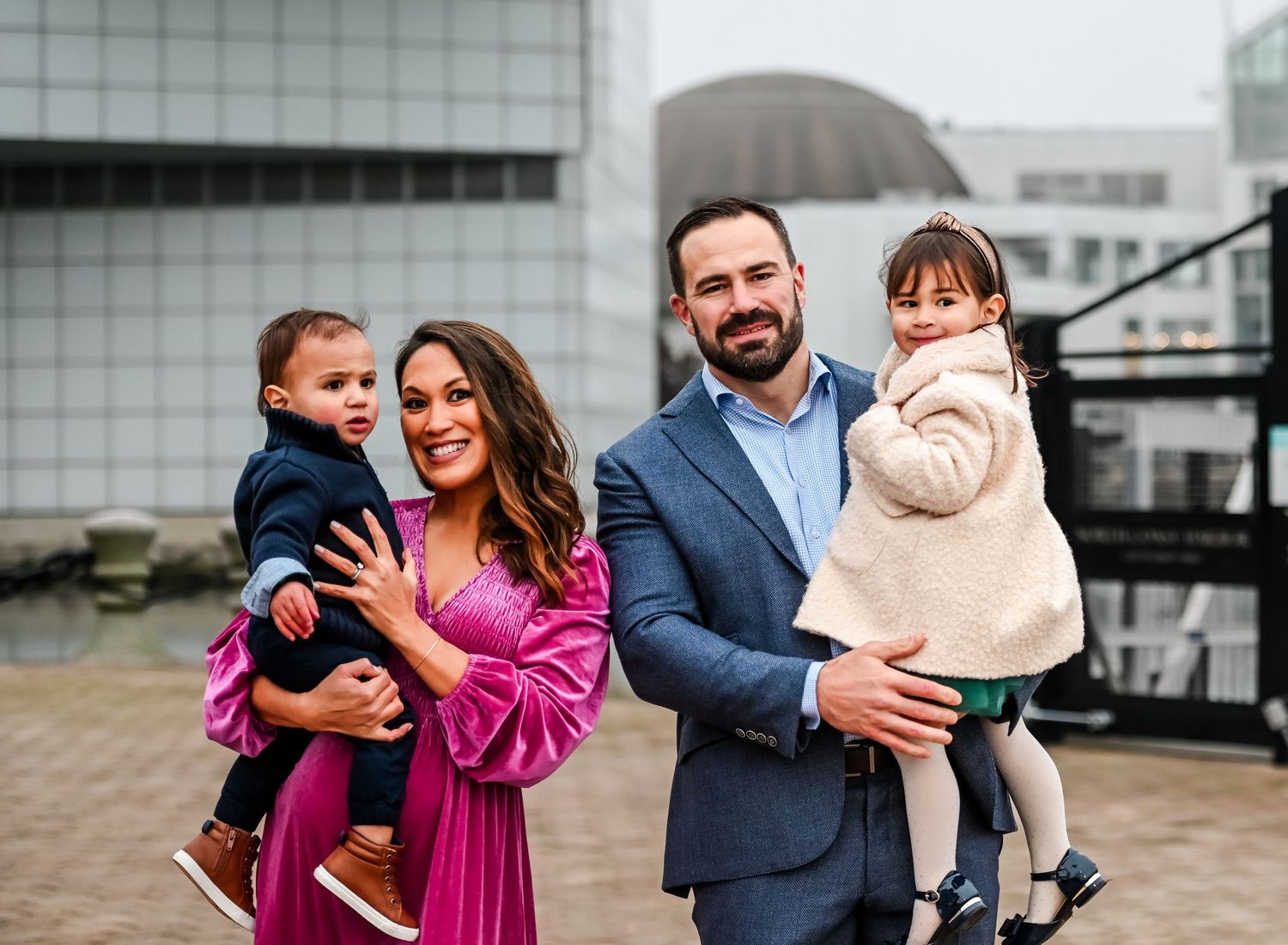 Family of four poses together outdoors in formal attire.