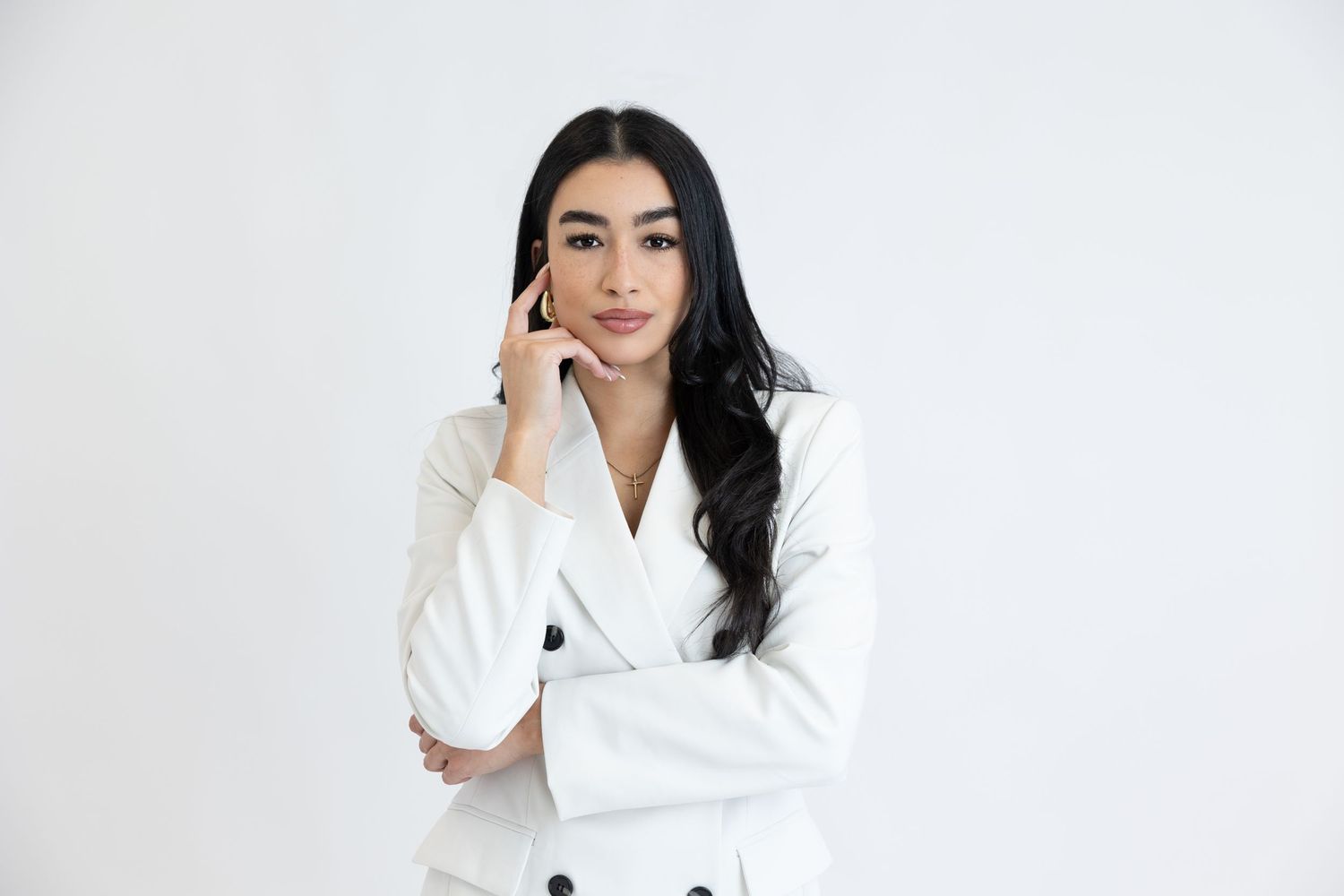 Professional portrait of woman in white blazer against white background.