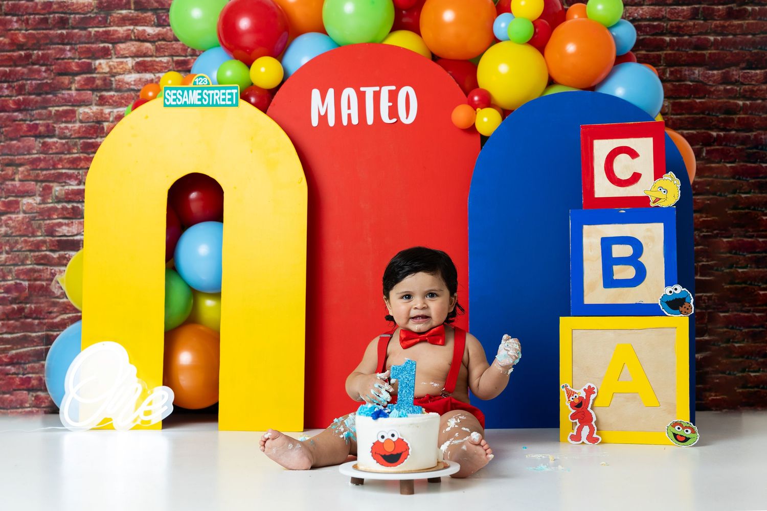 Colorful Sesame Street themed first birthday setup with alphabet blocks and balloons.