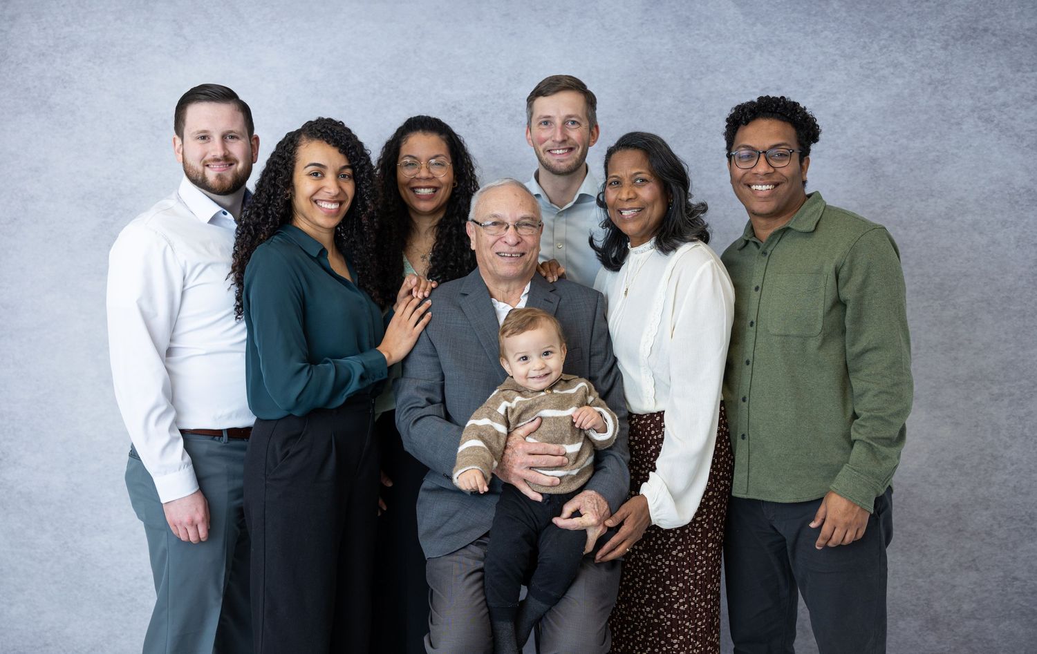 Studio portrait of diverse family group with two children against grey backdrop.