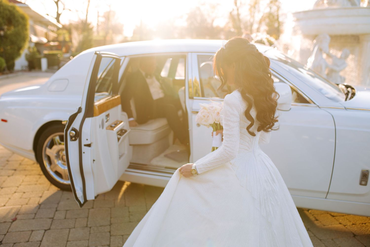 A romantic sunset wedding scene with a white limousine and flowing bridal veil.