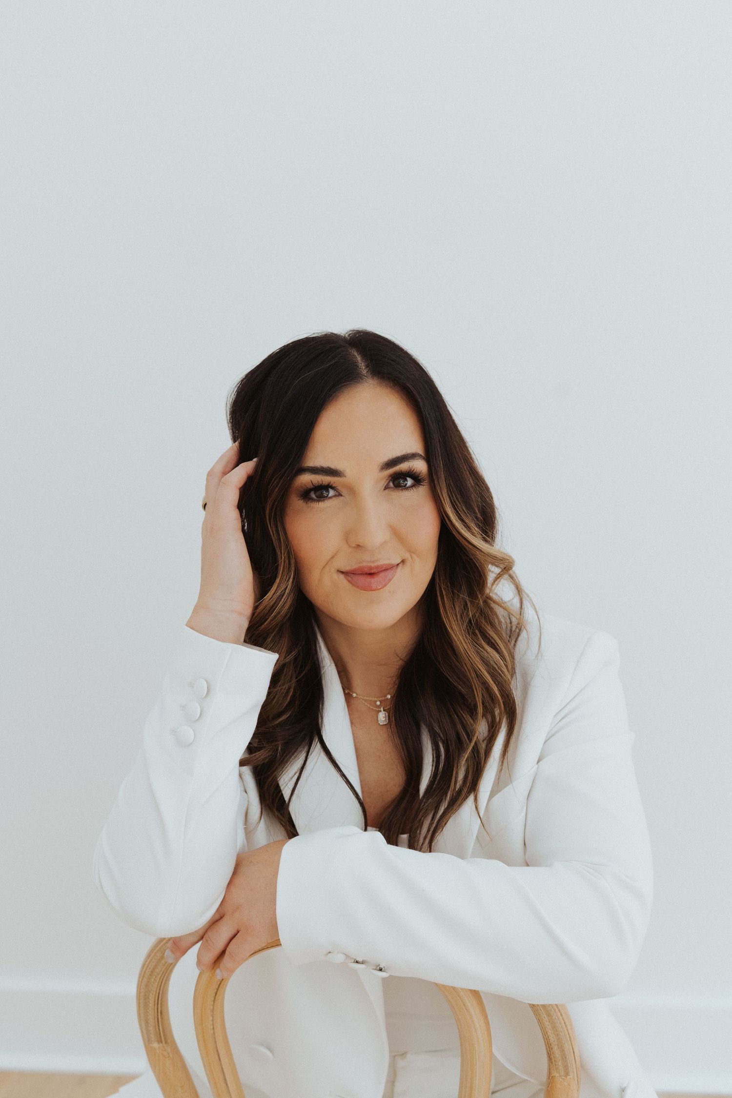 Woman in white blazer posing against light background in professional headshots.